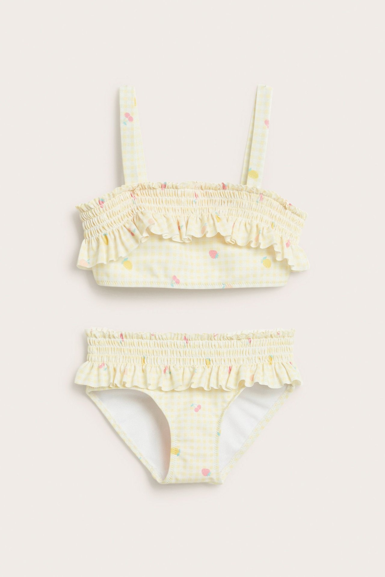 Widok z przodu dziecięcego żółtego bikini w kratkę z marszczoną gumką, falbankami i kolorowym wzorem owoców.