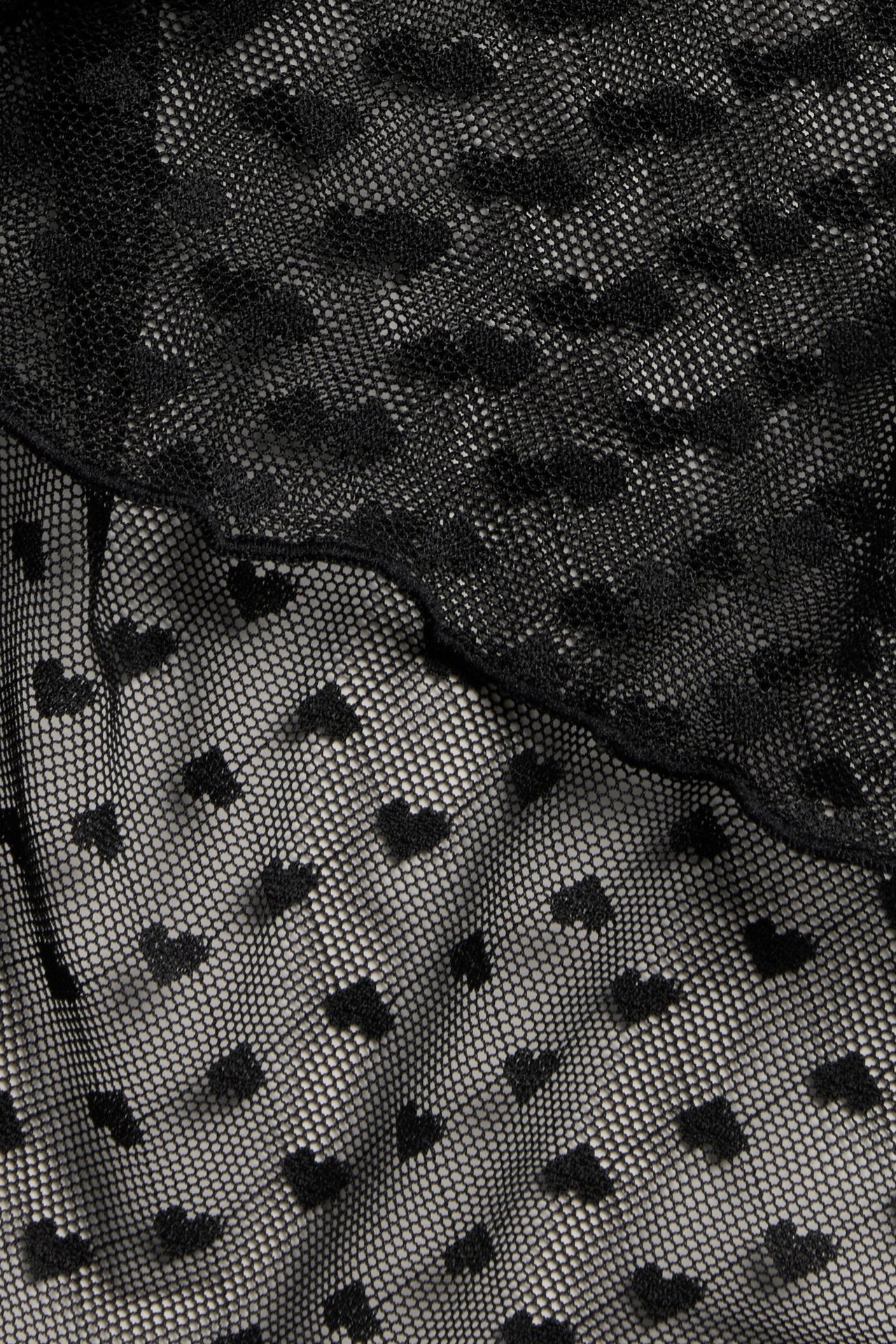 Musta sydän-kuvioinen mesh-liivi, läheltä, istuu hyvin, joustava materiaali.