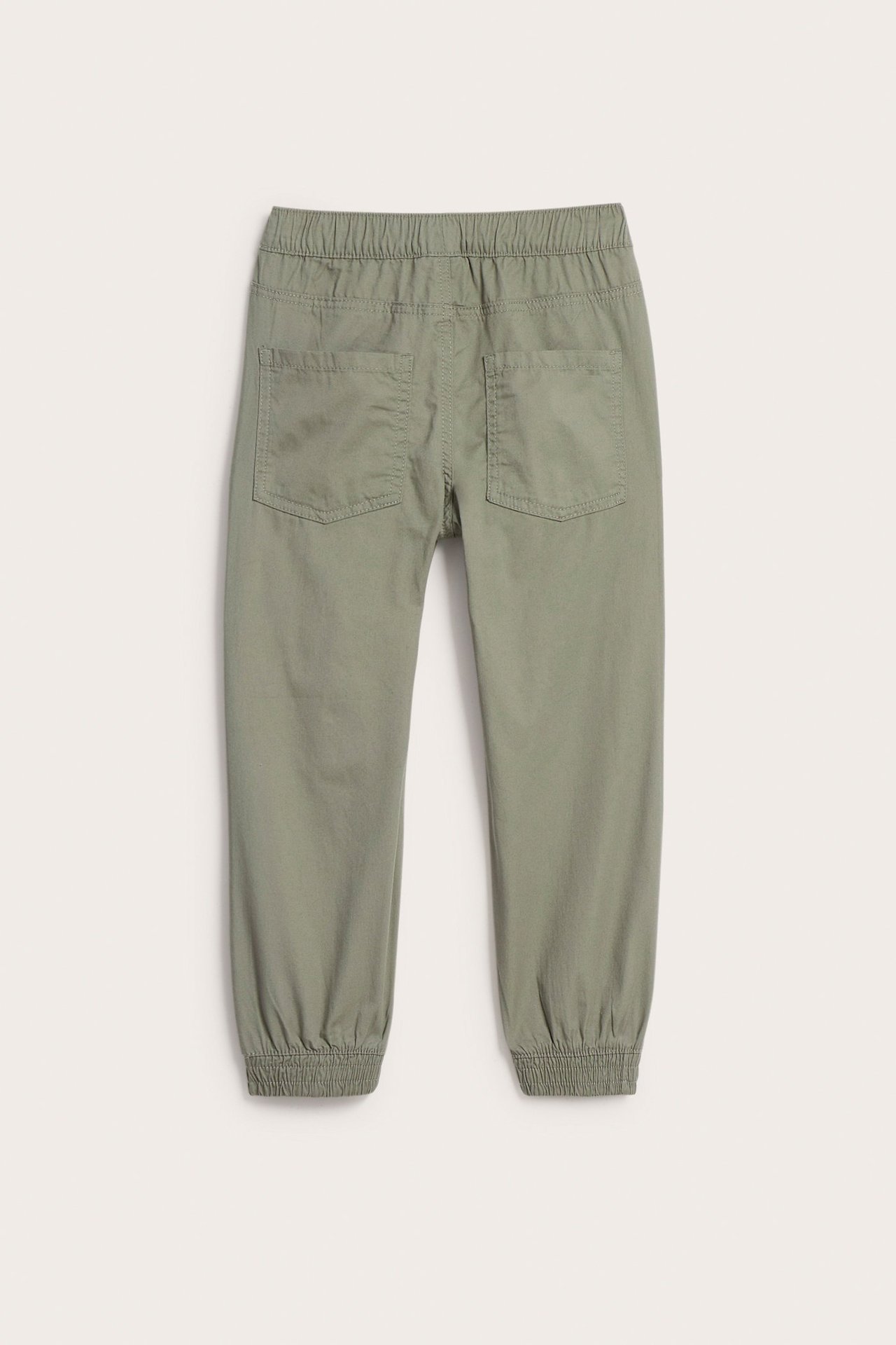 Bakifrån av barnens khakigröna bomullsbyxor med resår i midjan, två bakfickor och muddar.