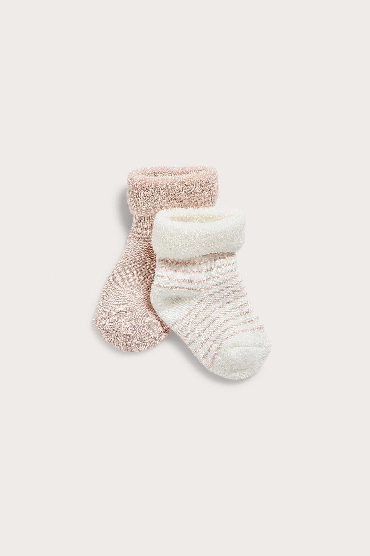 Framifrån, två babyfrottéstrumpor: en ljusrosa, en vit med ljusrosa ränder och vikta muddar.