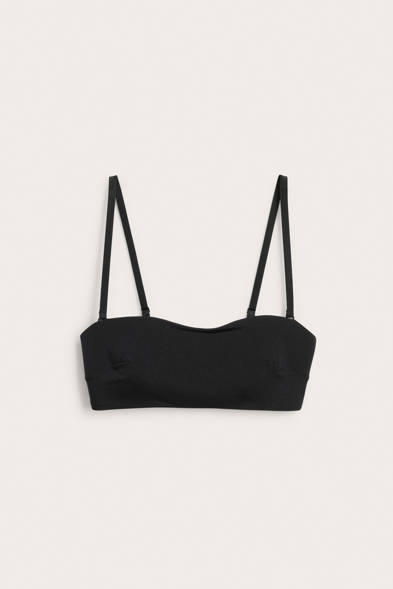 Forfra, en svart mykt polstret bandeau-BH med justerbare, avtakbare stropper.