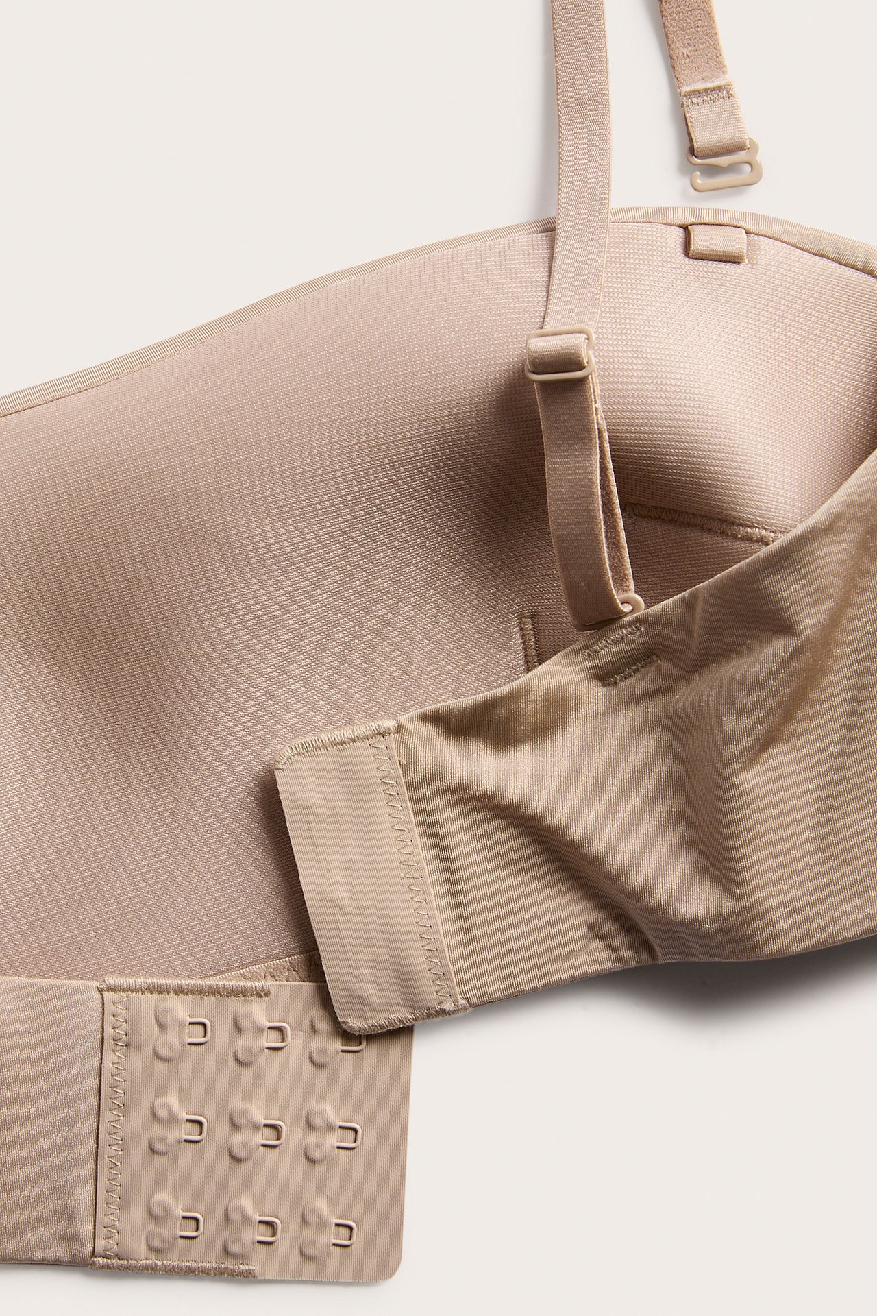 Nærbilde av en brun polstret bandeau-BH med avtakbare stropper og hektefeste.