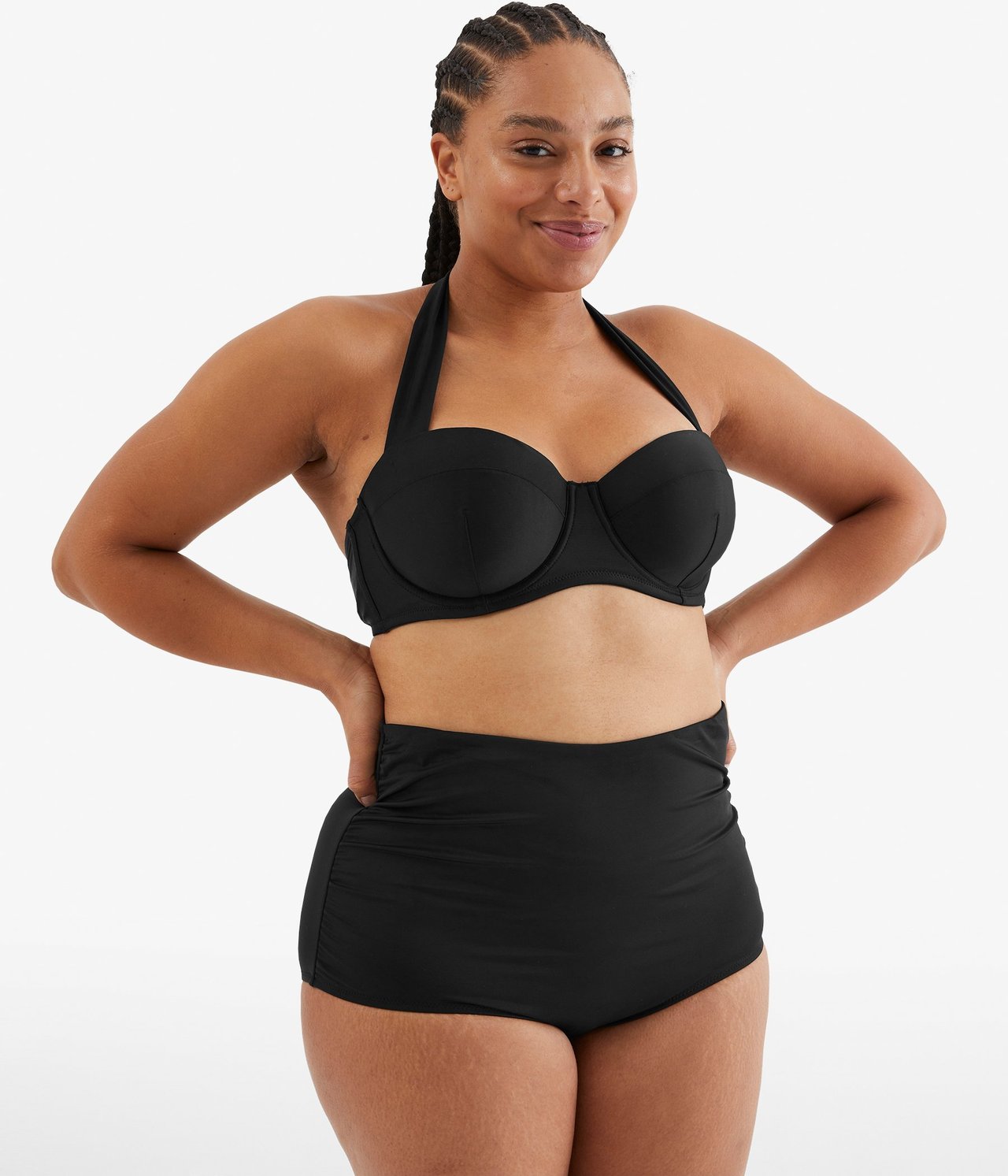Widok z przodu: kobieta w czarnych, wysokich figach bikini z marszczeniami i czarnym biustonoszu halterneck.