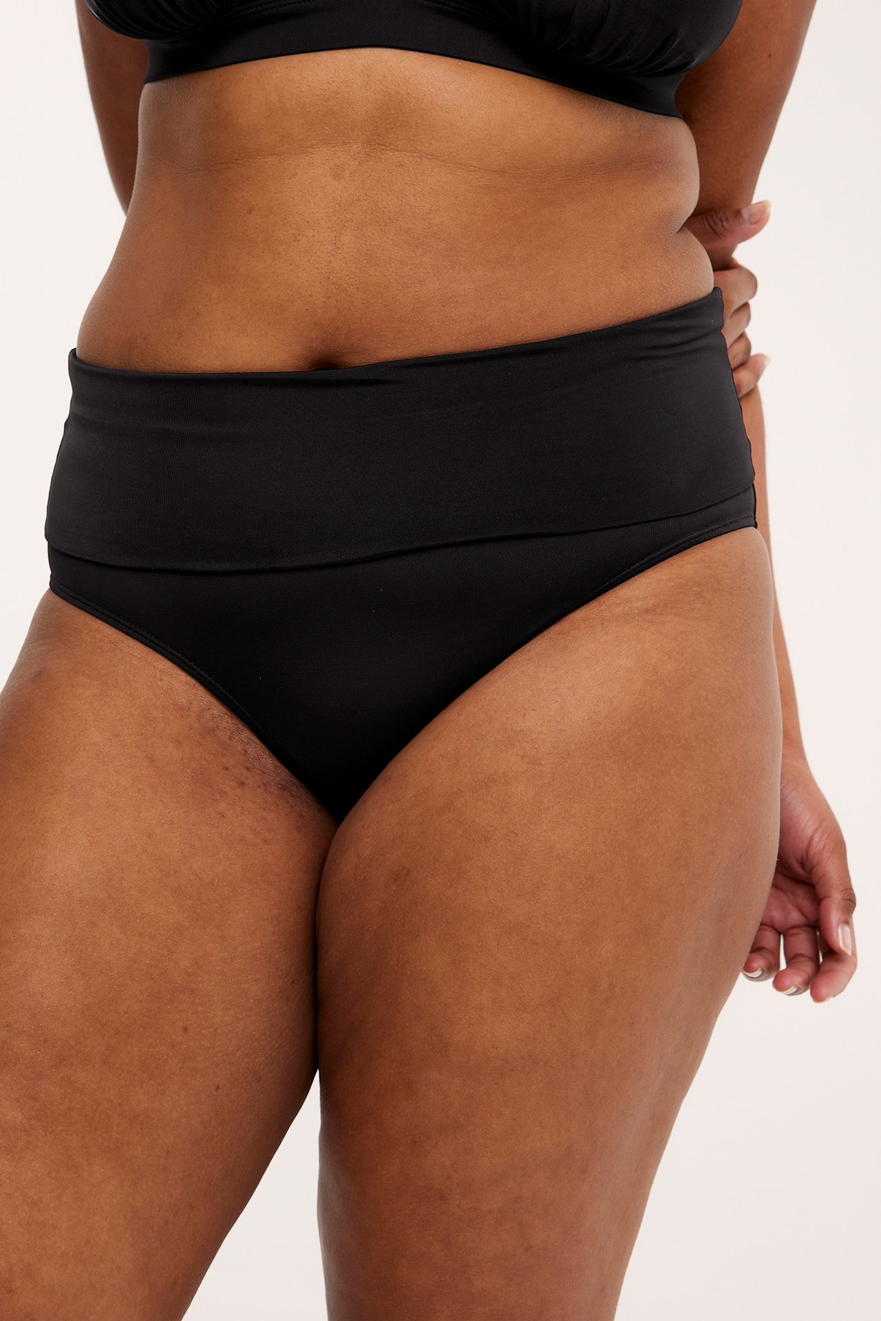 Närbild framifrån på en kvinna i svart vikbar bikinitrosa och matchande svart bikinitopp.