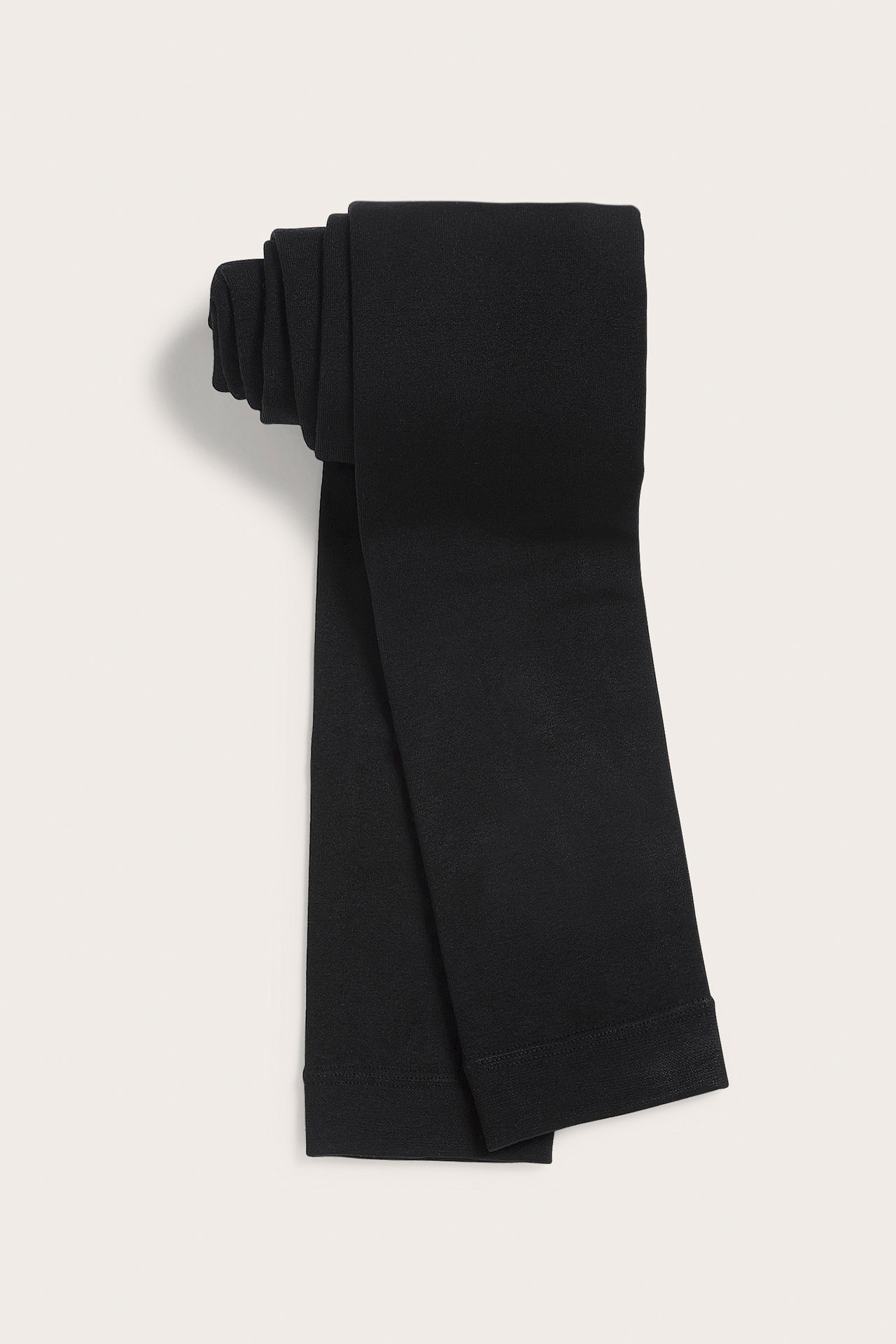 Taitetut mustat läpinäkymättömät leggingsit, litteä etunäkymä.