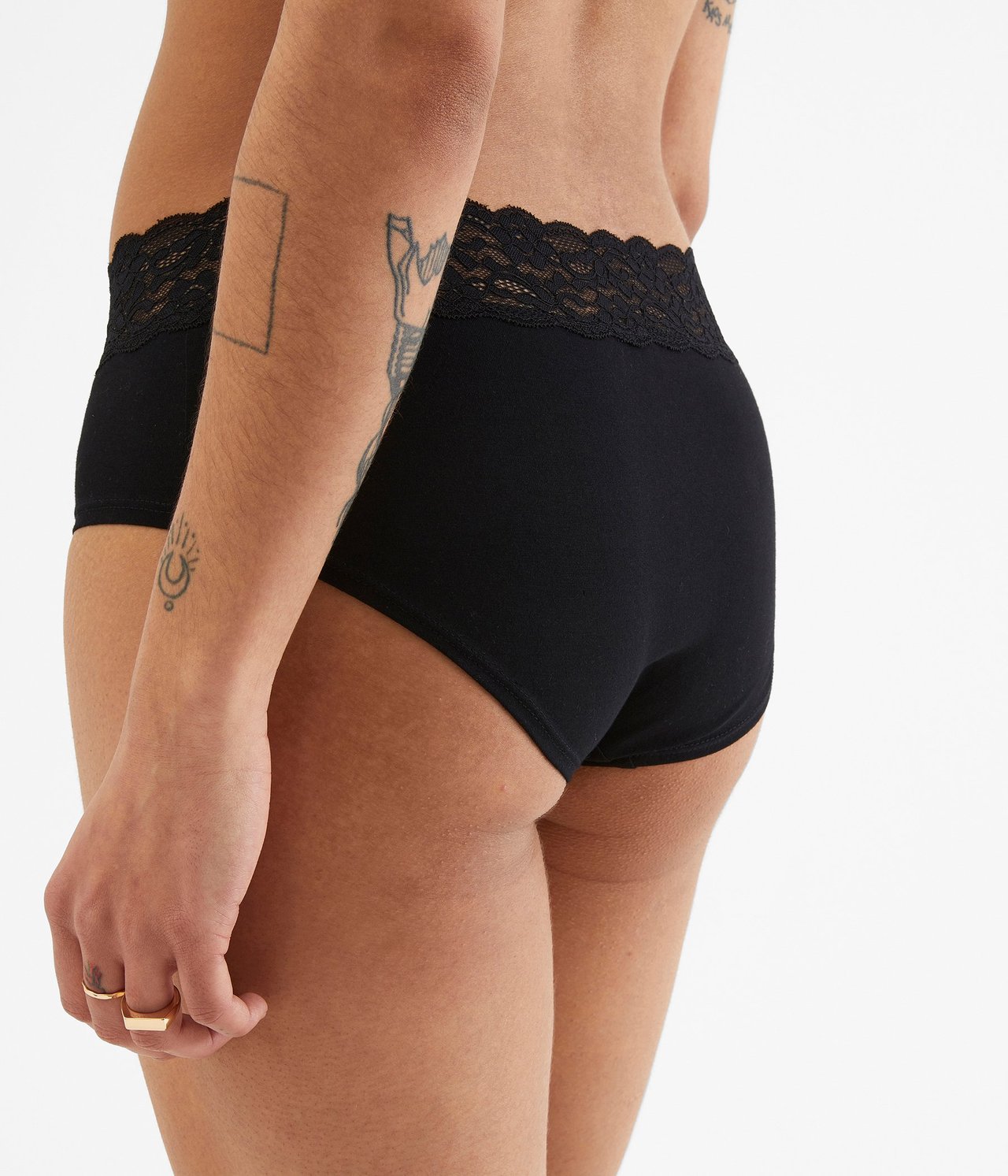 Widok z boku kobiety w czarnych bawełnianych figach typu hipster z koronkowym pasem.