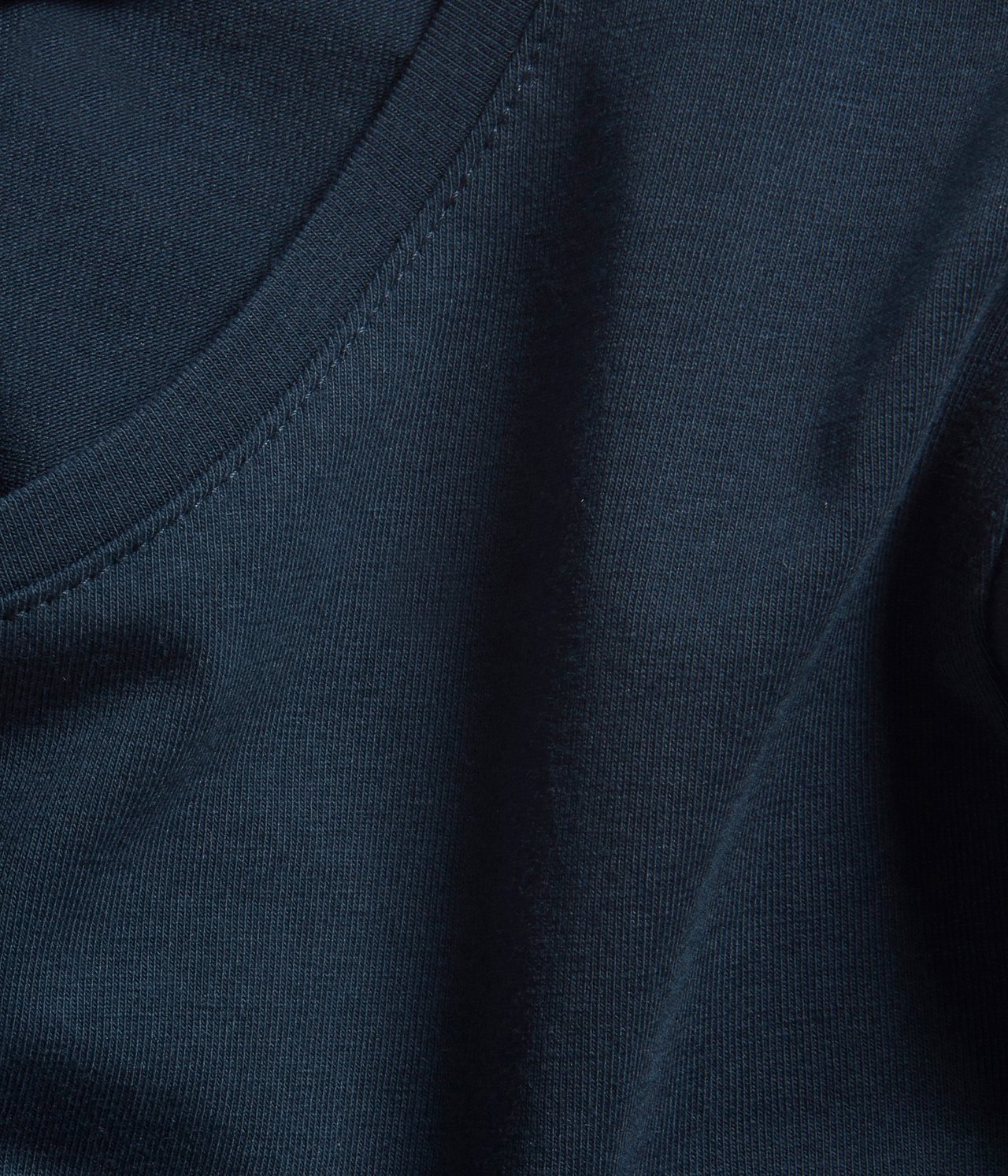 Nærbilde av en mørkeblå langermet basetopp med rund hals og ribbet tekstur.