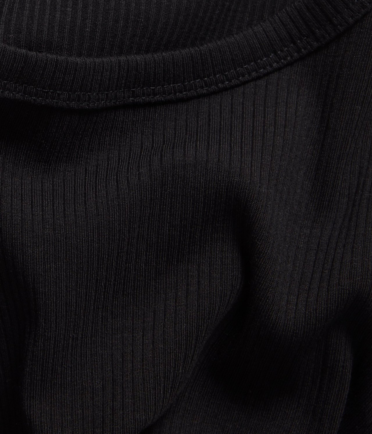 Zbliżenie czarnego prążkowanego topu, ukazujące teksturowany materiał i okrągły dekolt.