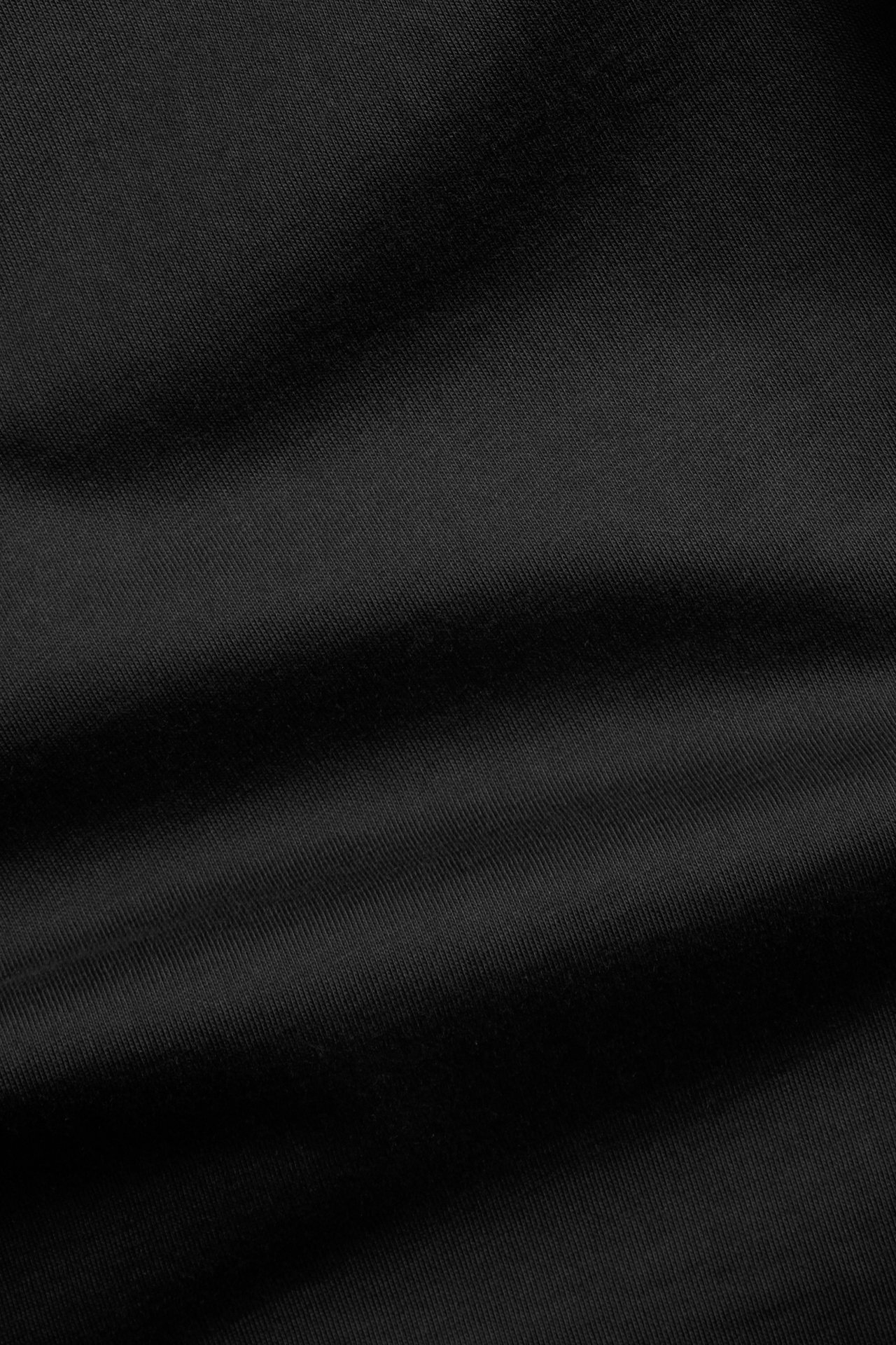 Zbliżenie na czarny, jednolity materiał bawełniany, prawdopodobnie z koszulki T-shirt o prostym kroju.