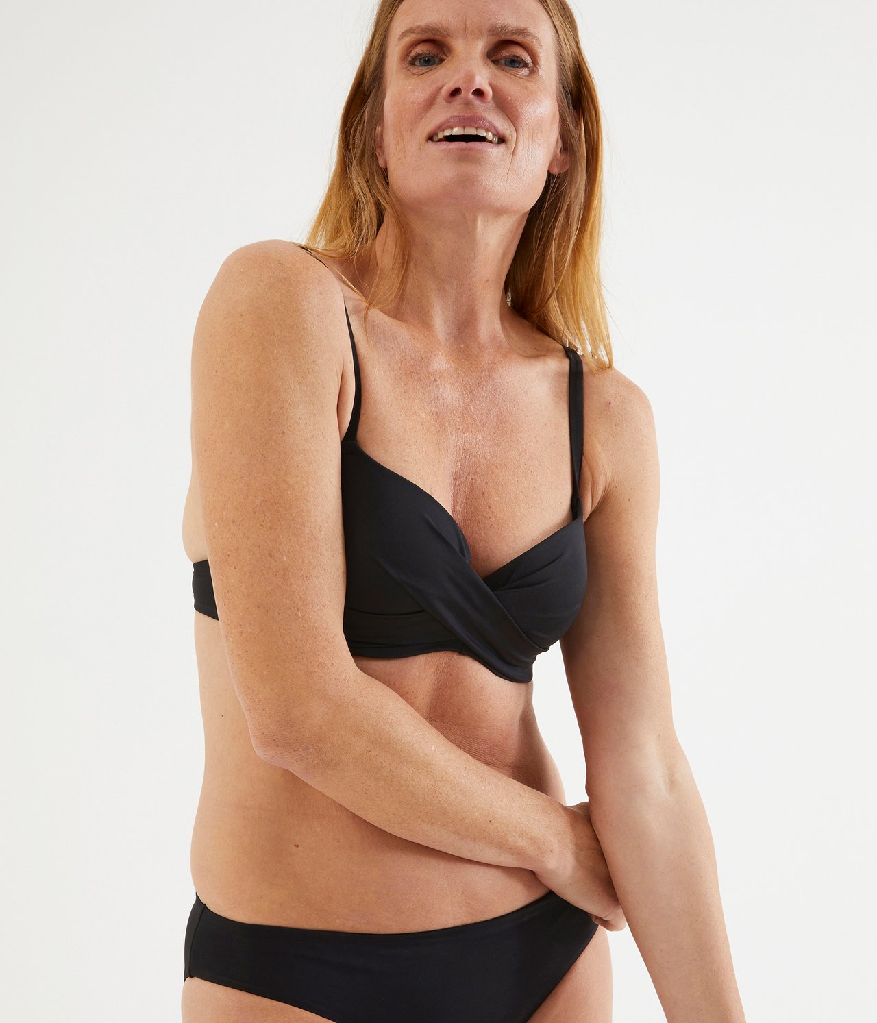 Forfra: Kvinne i svart ensfarget bikinitopp med vridd front og matchende underdel.