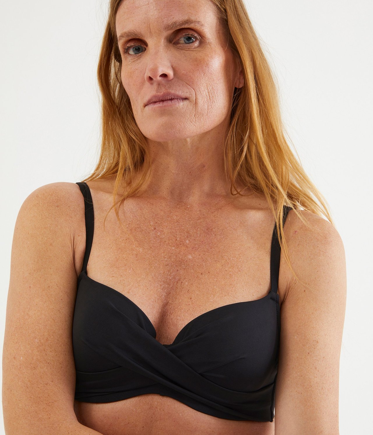 Zbliżenie z przodu kobiety w czarnym, jednolitym biustonoszu bikini ze skręconym detalem i regulowanymi ramiączkami.