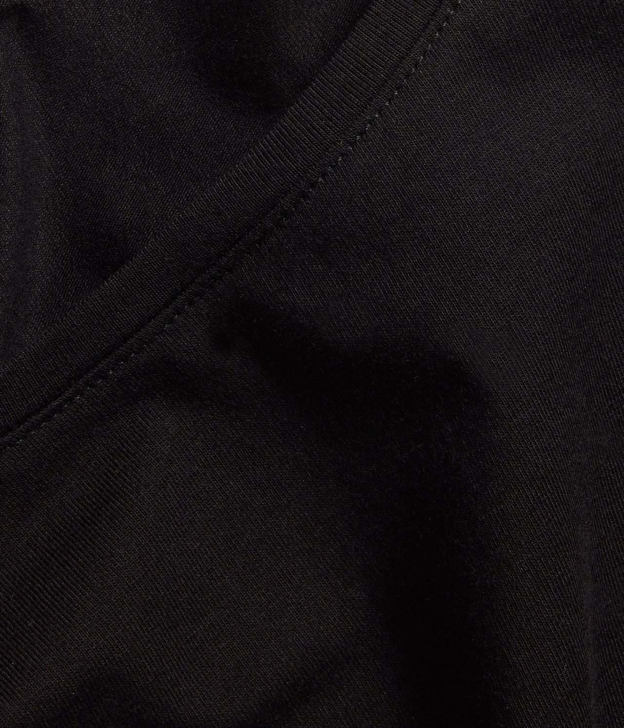 Nærbilde av en svart kortermet basetopp, som viser den runde halslinningen og sømmene.