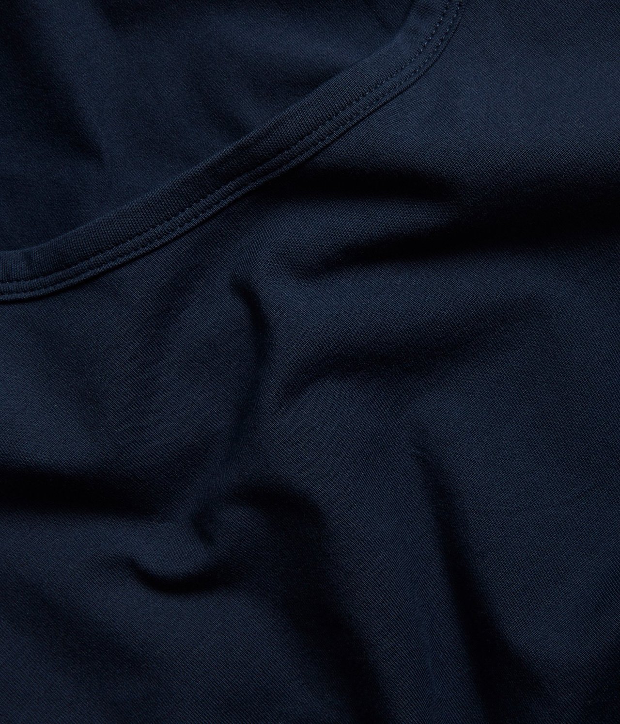 Zbliżenie na granatowy, elastyczny bawełniany top basic, ukazujące dekolt.