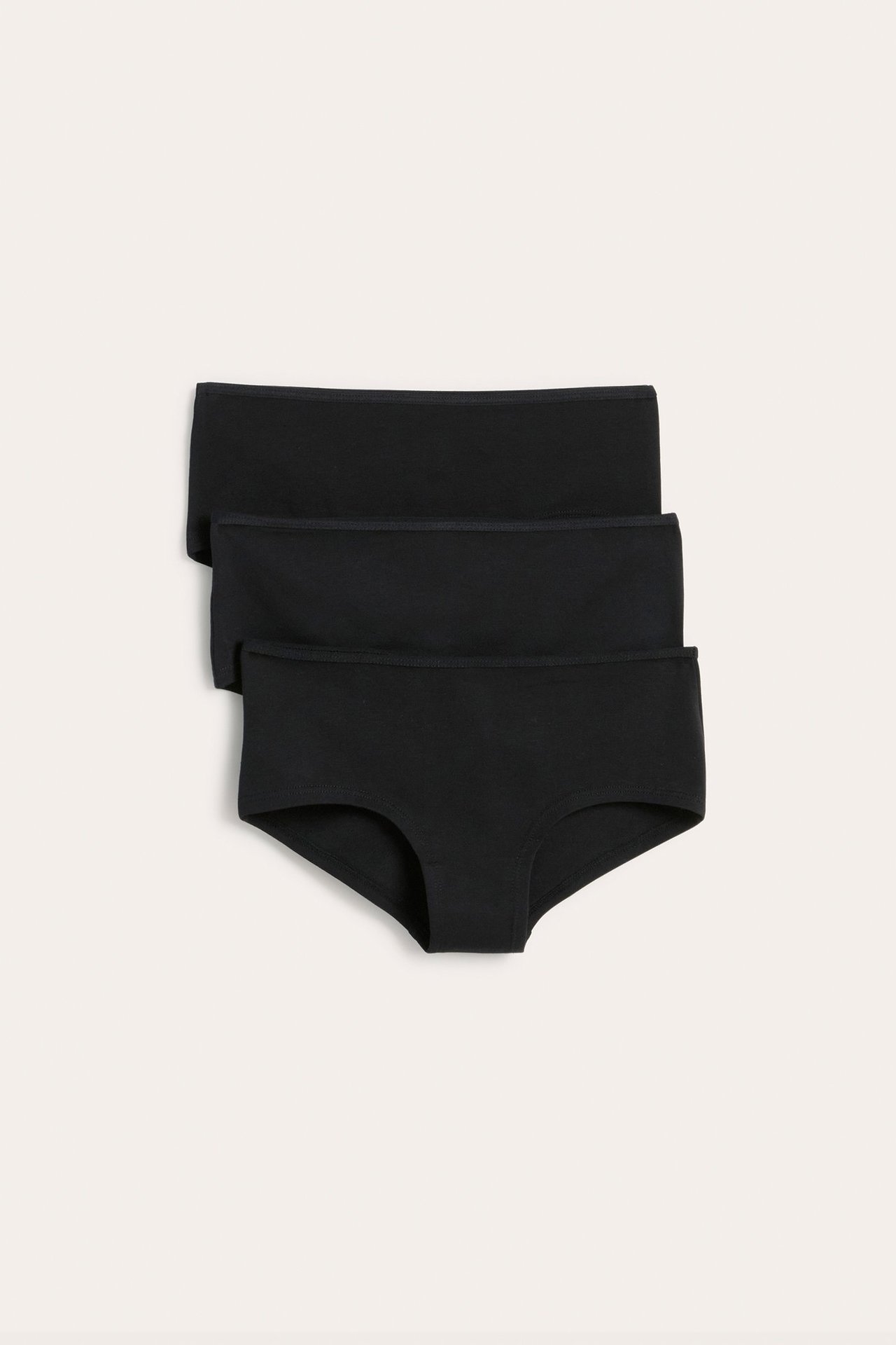 Edestä kolme mustaa yksiväristä hipster-alushousua kapeilla kuminauhoilla, pinottuna.