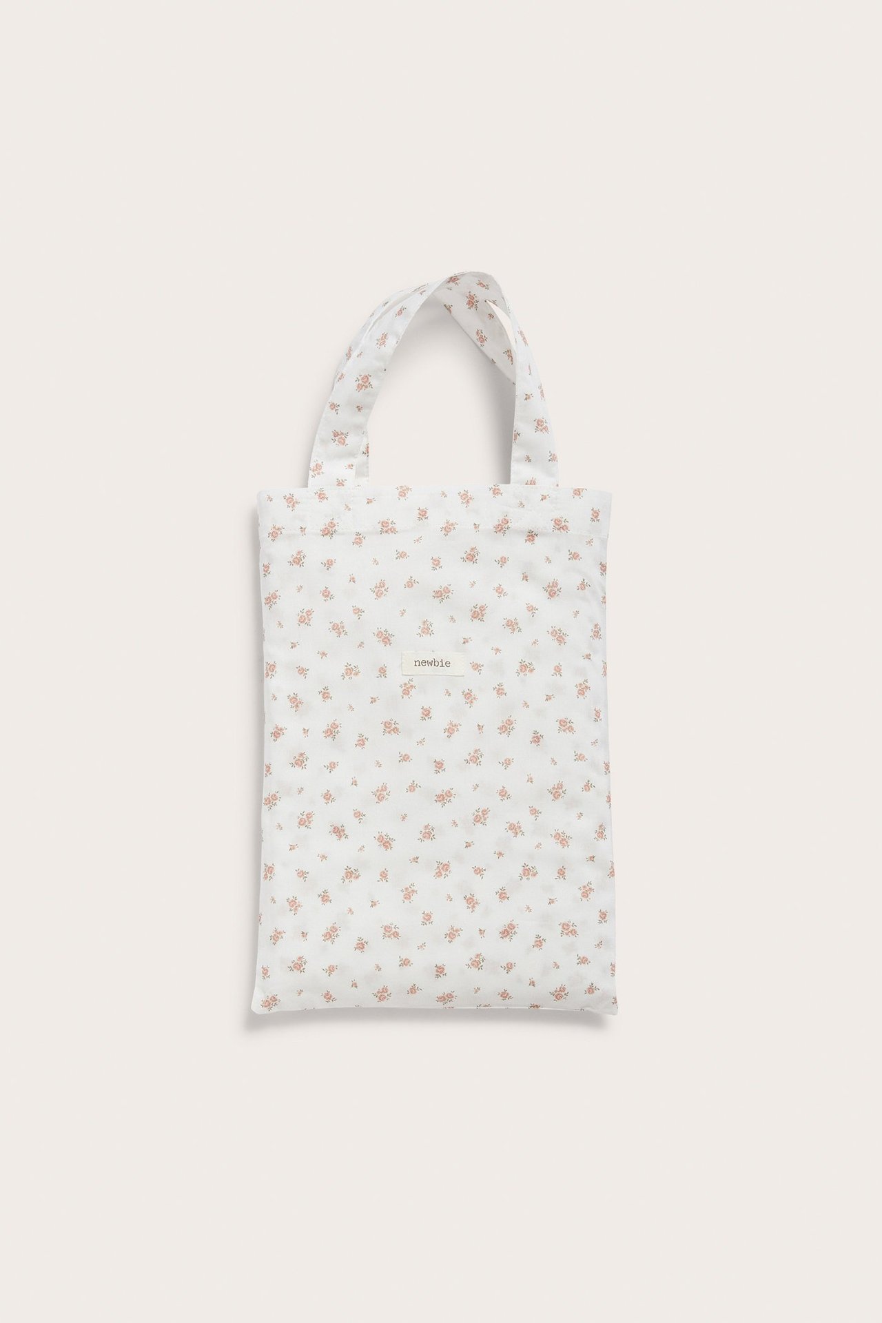 Framsida av en offwhite bomullstygpåse med småblommigt mönster och en 'newbie'-logga.