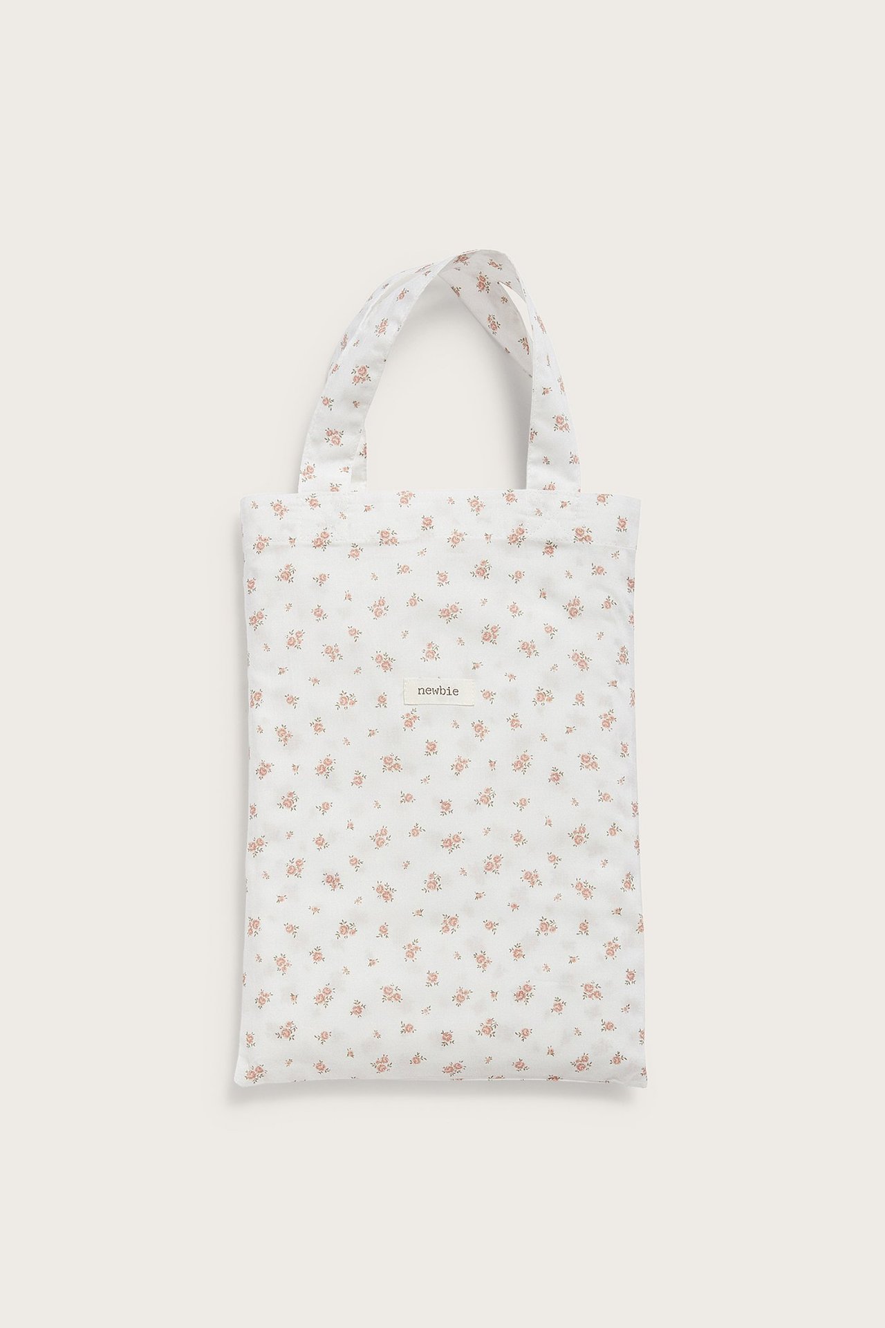 Frontvisning av et brettet offwhite bomullsengesett med et lite rosa blomstermønster.