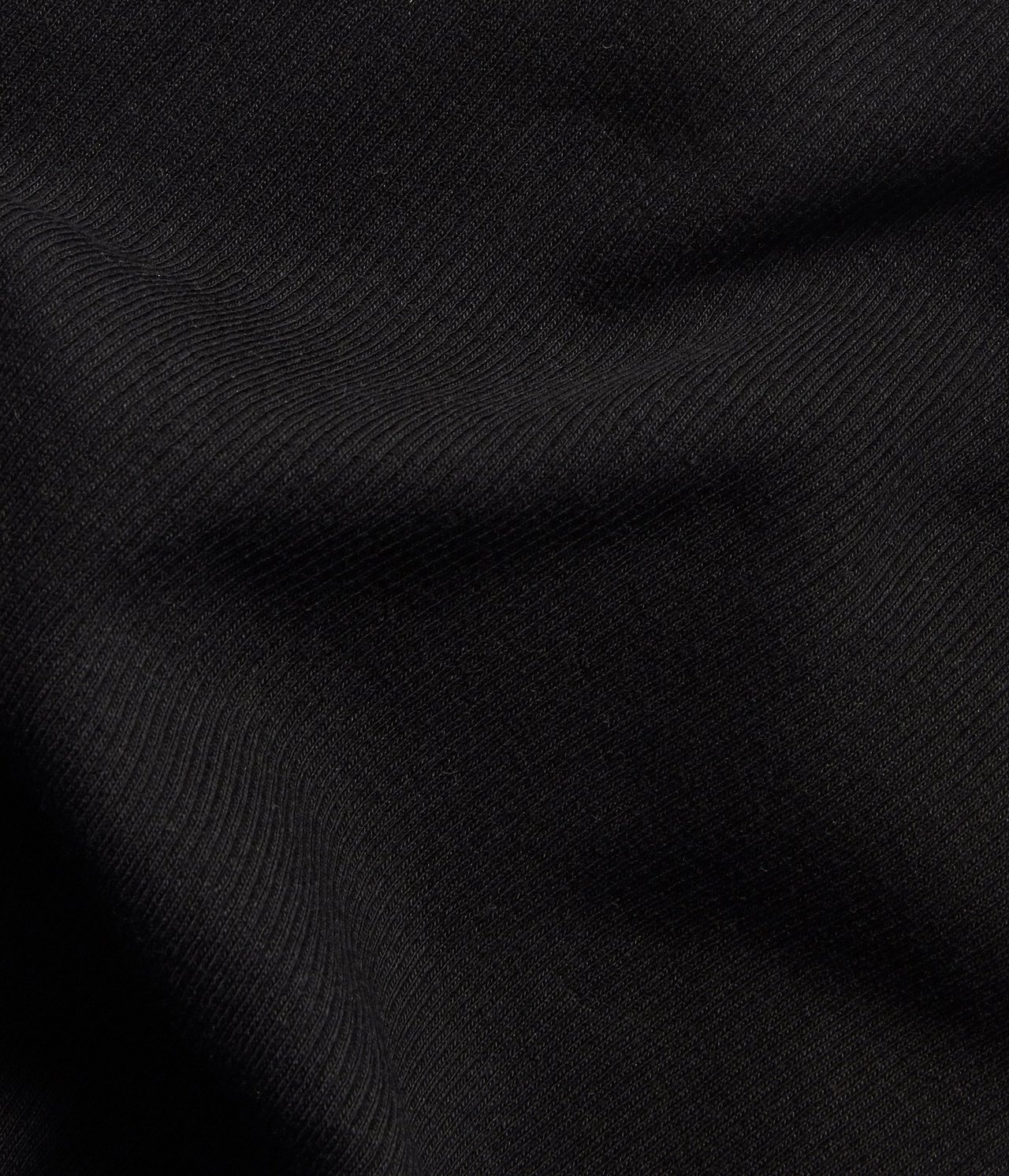 Zbliżenie na czarny prążkowany materiał topu, ukazujące jego teksturowany wzór.