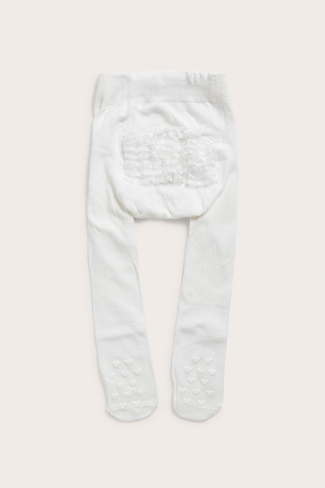 Mjuka offwhite strumpbyxor med spetsvolang bak, anti slip, från Newbie, storlek 74/80.
