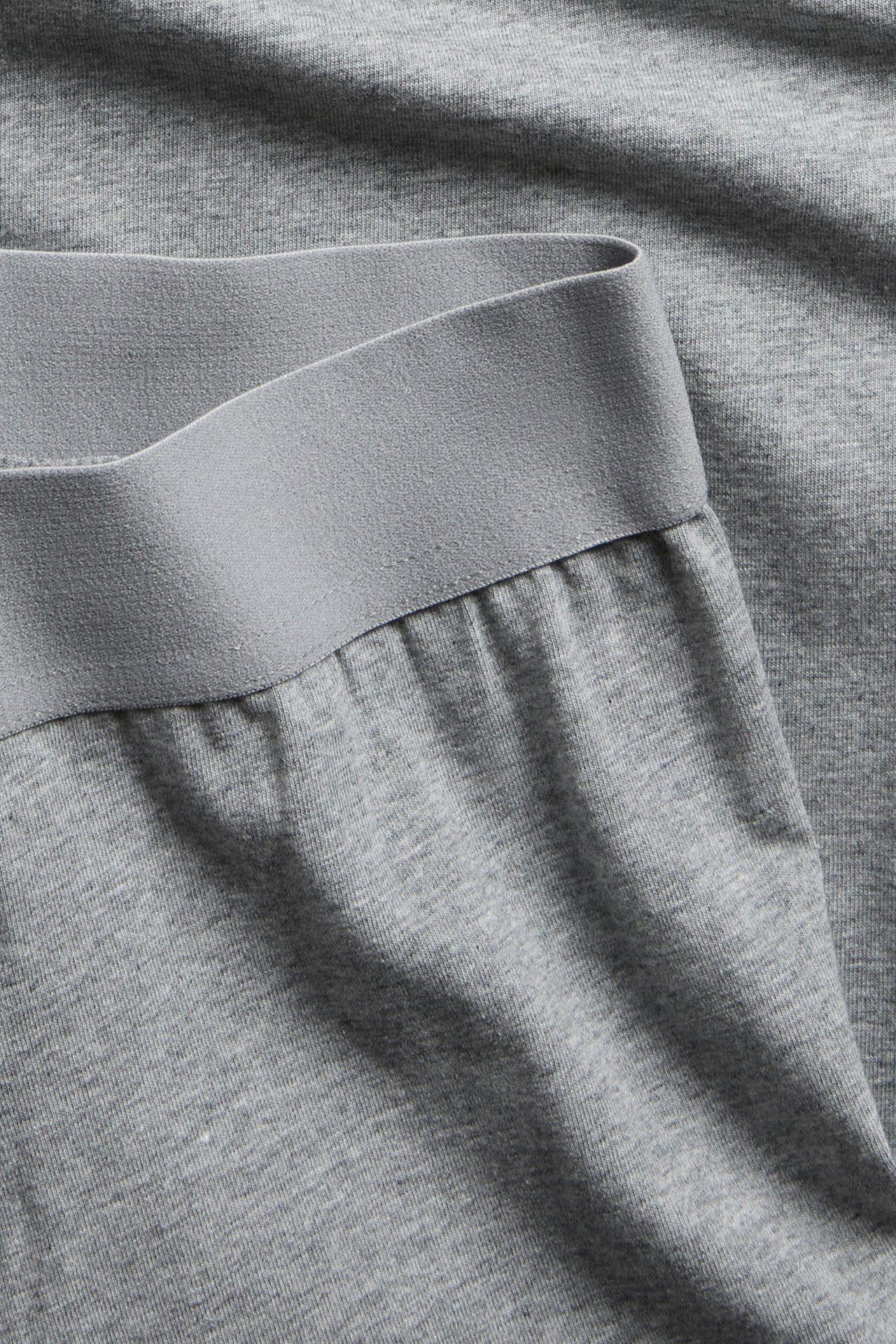 Närbild på ljusgråmelerade jersey shorts med resårlinning.
