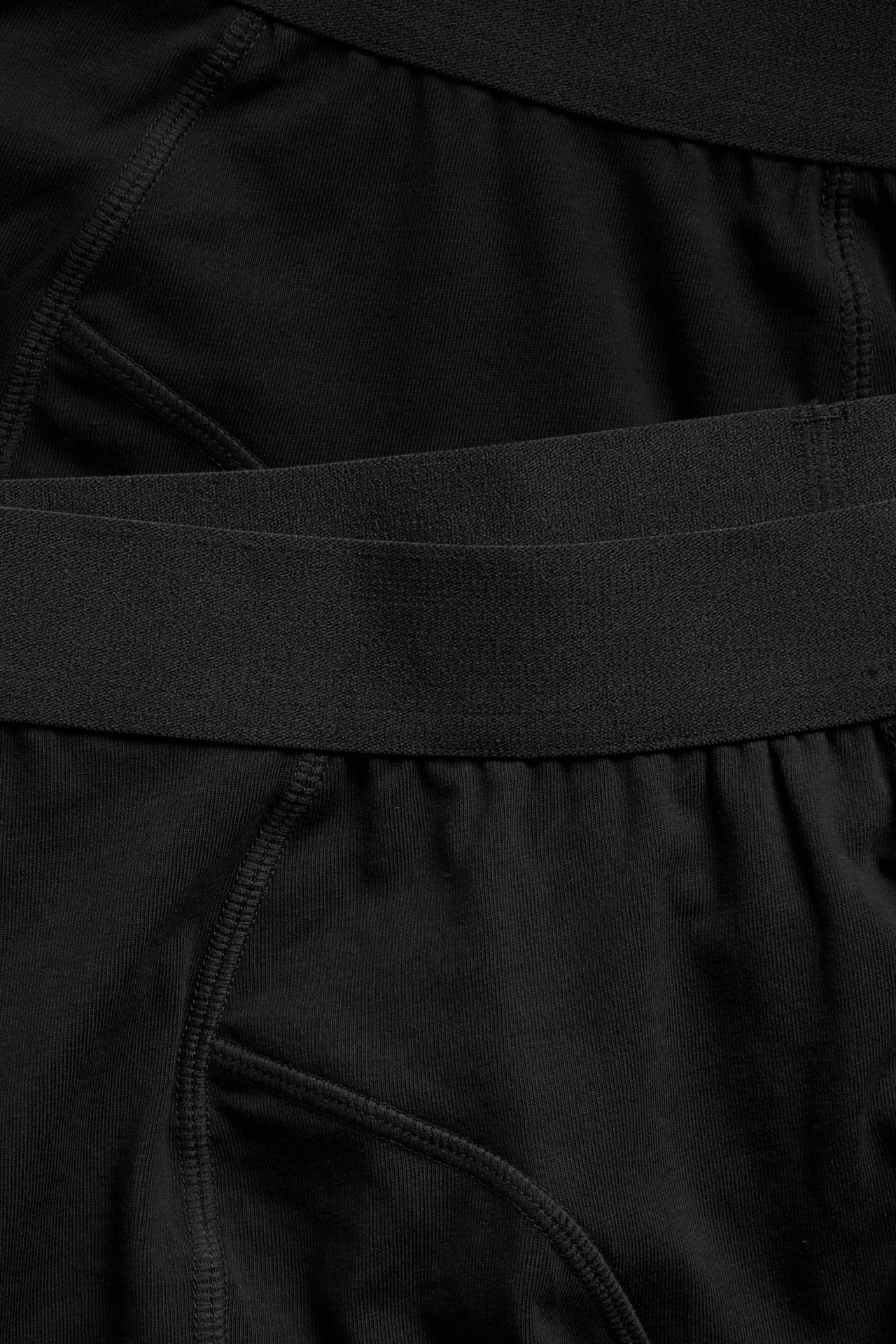 Närbild av två par svarta bomullsboxershorts för män med elastiska midjeband.