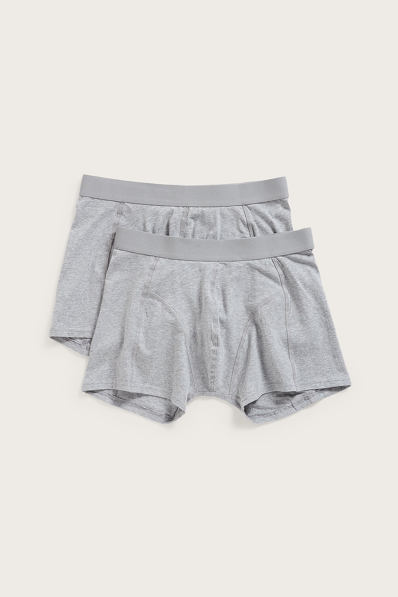 Frontvy av två par enfärgade gråmelerade kalsonger för män med resår i midjan, plattlagda.