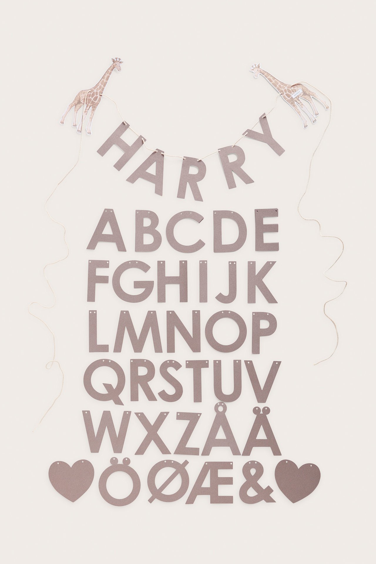 Ovenfra: brunt papirgirlandesett med bokstaver, to mønstrede sjiraffer og snor.