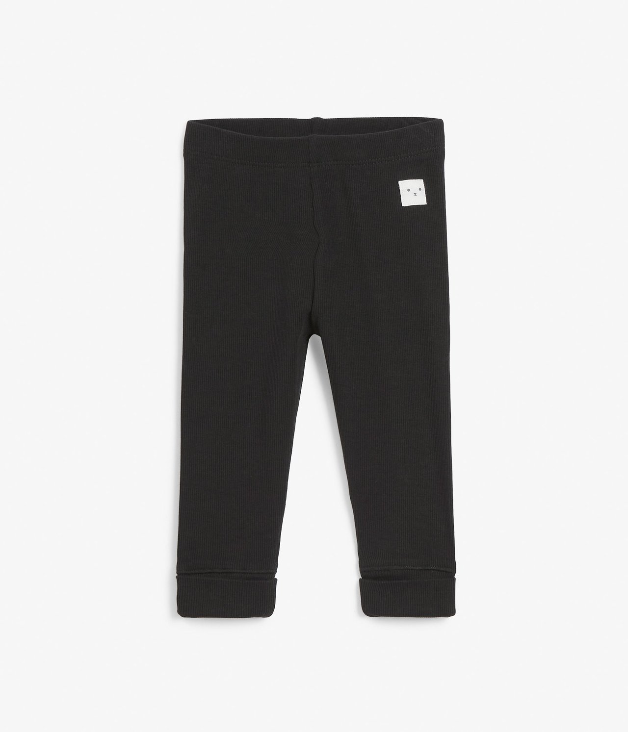 Framifrån: svarta ribbade baby leggings med resår i midjan, uppvikta muddar och en liten vit etikett.