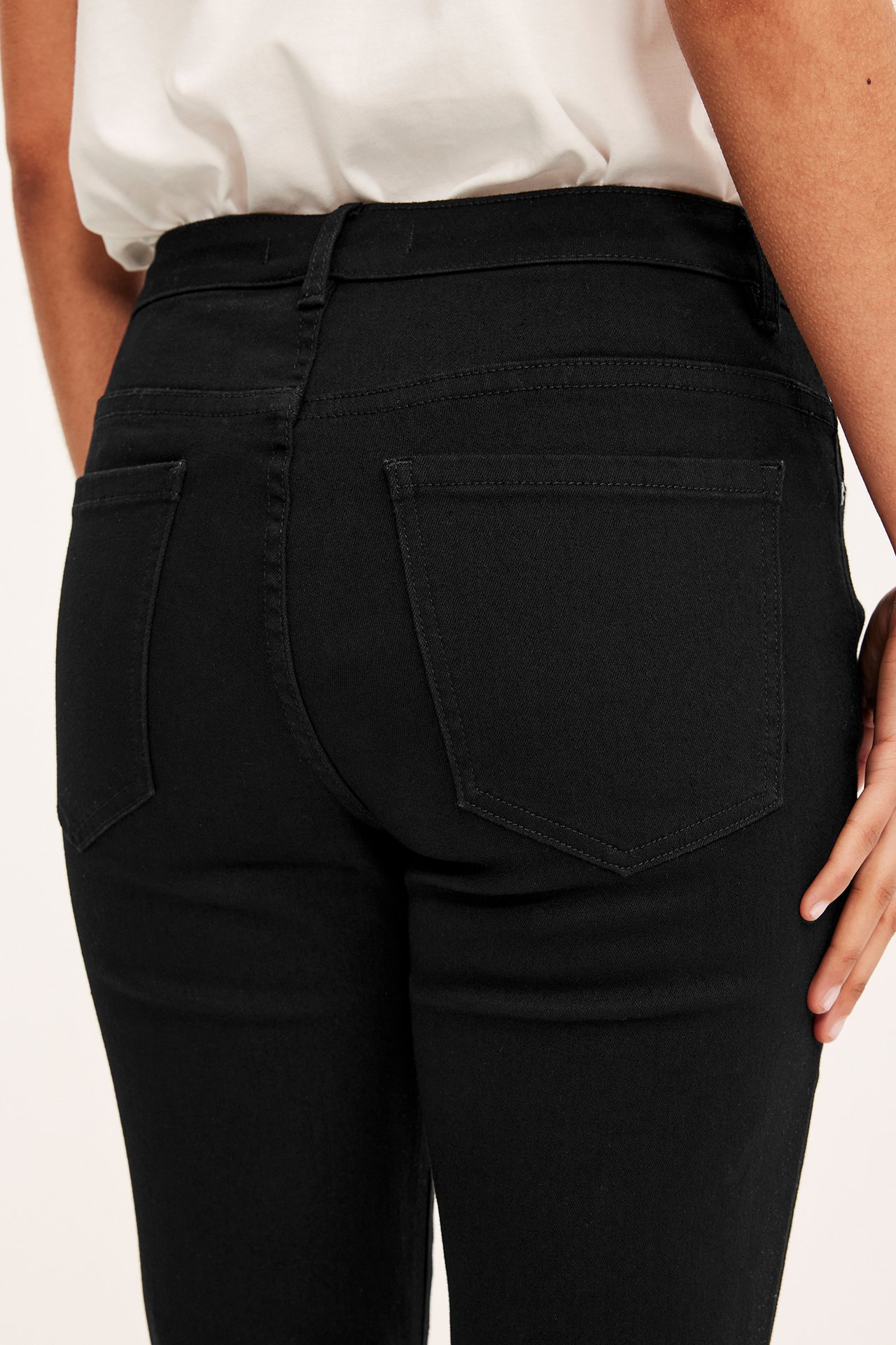 Nærbilde bakfra av en kvinne i svarte 5-lommers straight-fit jeans med normalt høyt liv.