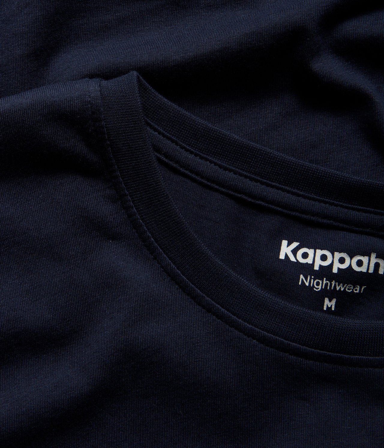 Zbliżenie na granatową męską bawełnianą piżamową koszulkę z okrągłym dekoltem.