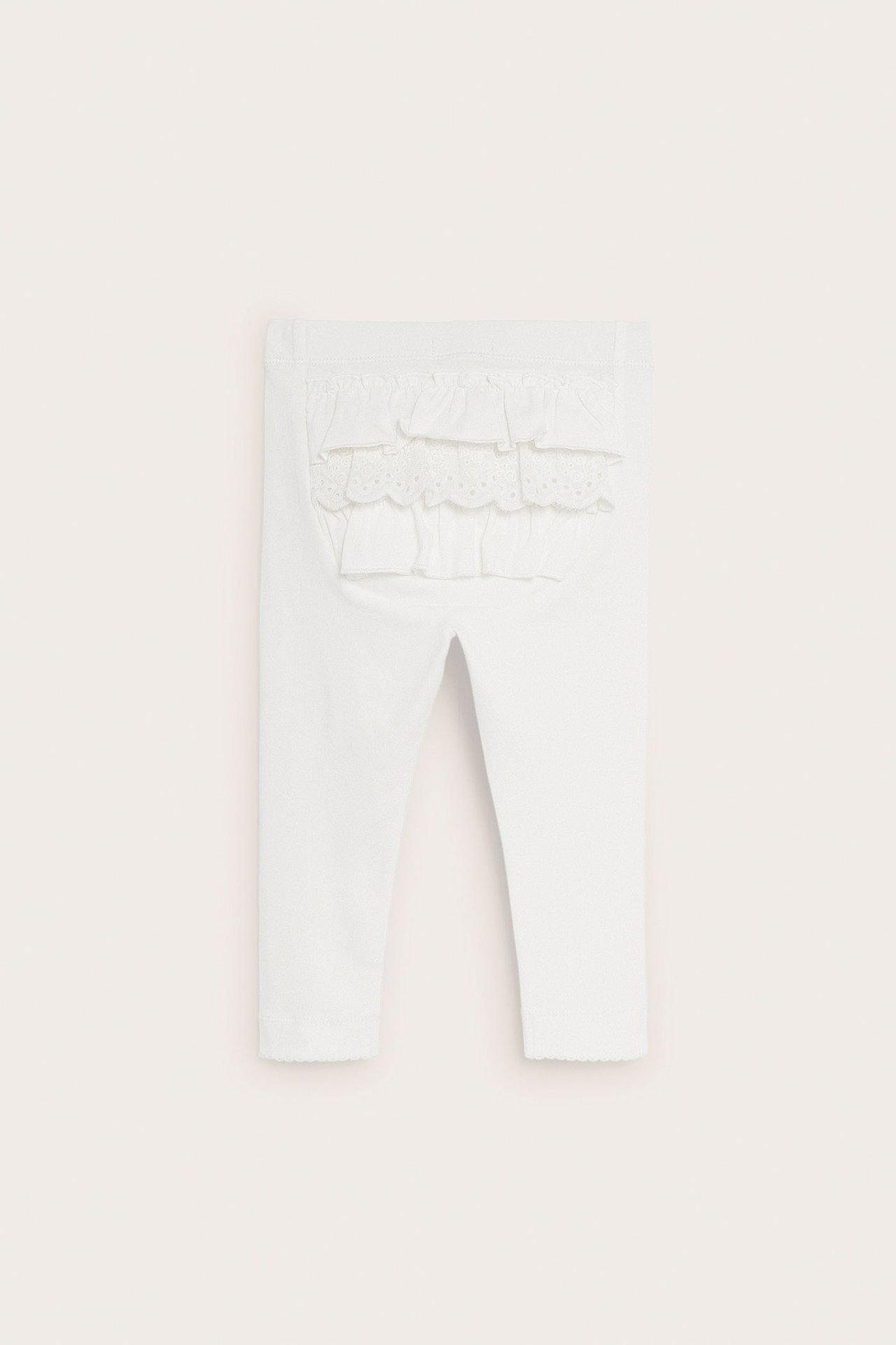 Bakfra: kremhvite baby-leggings med volanger og blonder bak, elastisk midje, picotkant.