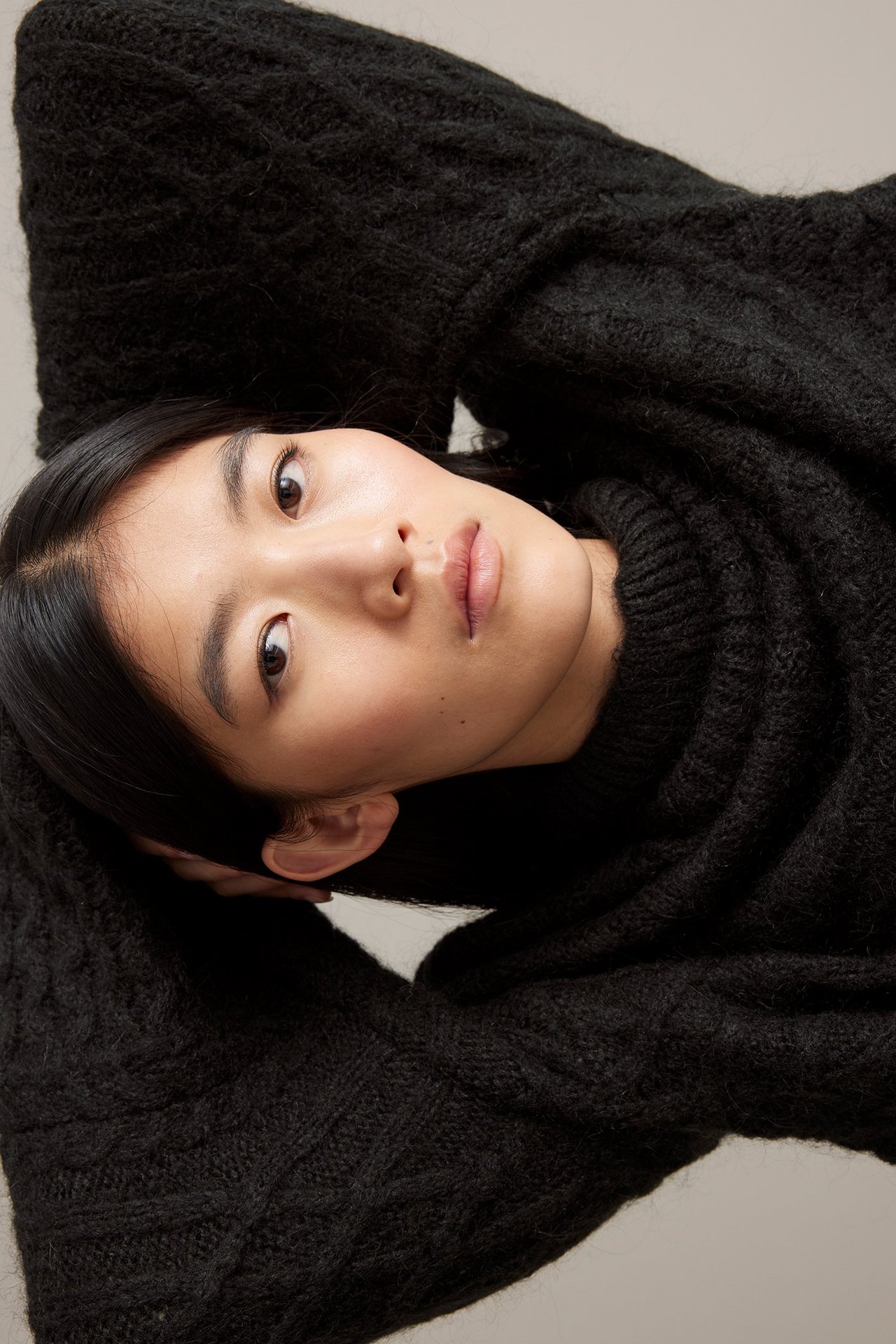 Nuori nainen mustassa sekoitevilla-polosukassa, makuuasennossa, etunäkymä.