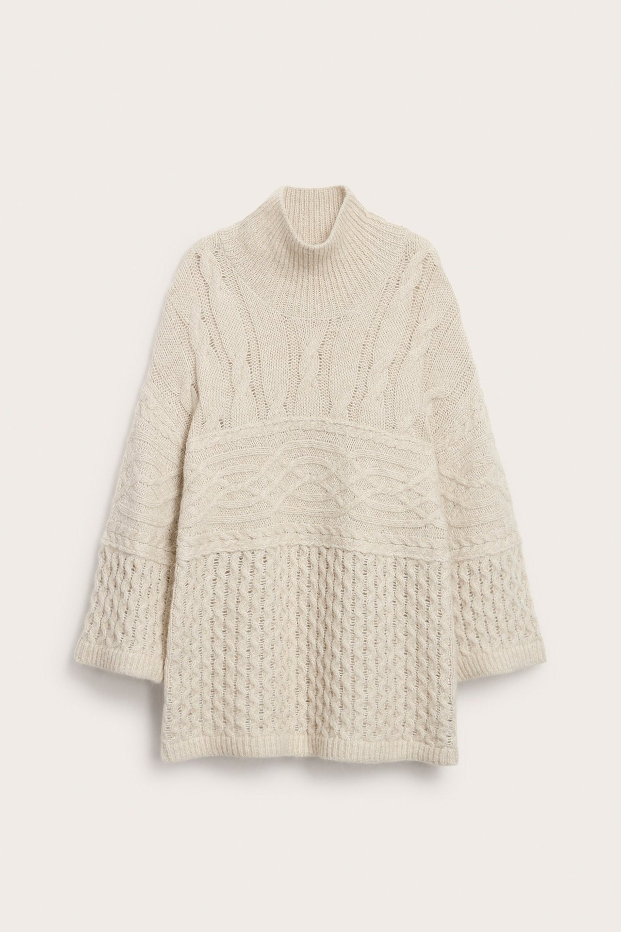 Edestäpäin vaaleabeige villasekoitteinen pooloneule, jossa on erilaisia palmikkoneulekuvioita.