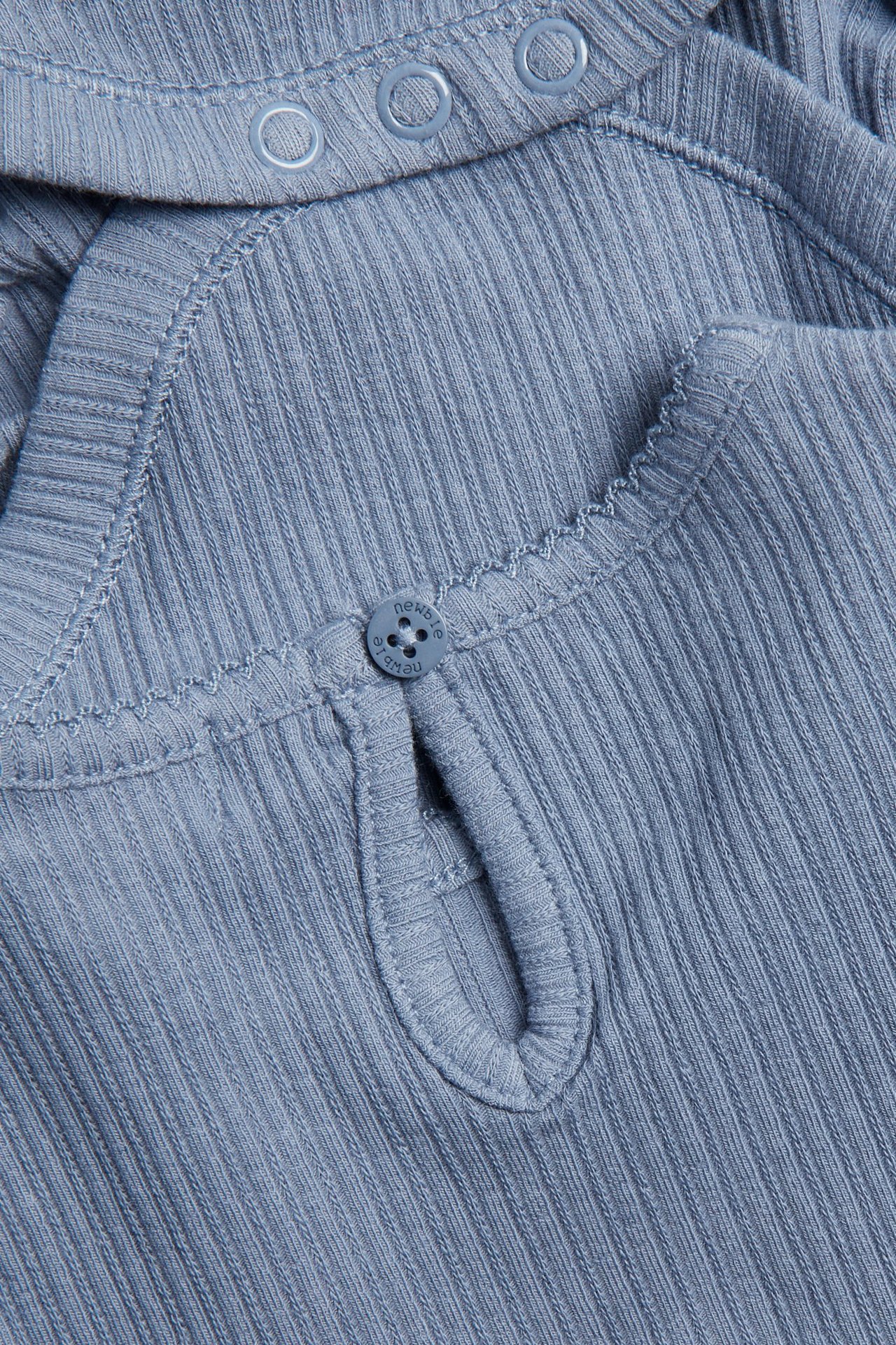 Nærbilde av en blå ribbet babybody med knappelukking bak og trykknapper på skulderen.