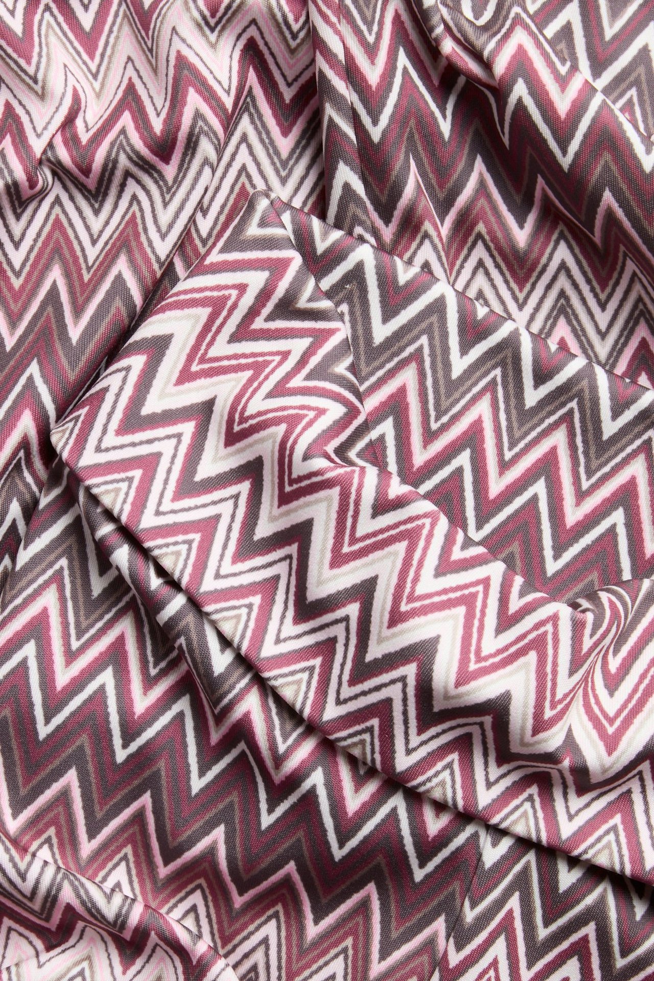 Zbliżenie na ciemnoczerwony, biały i brązowy materiał w zygzakowy wzór na legginsy dzwony.