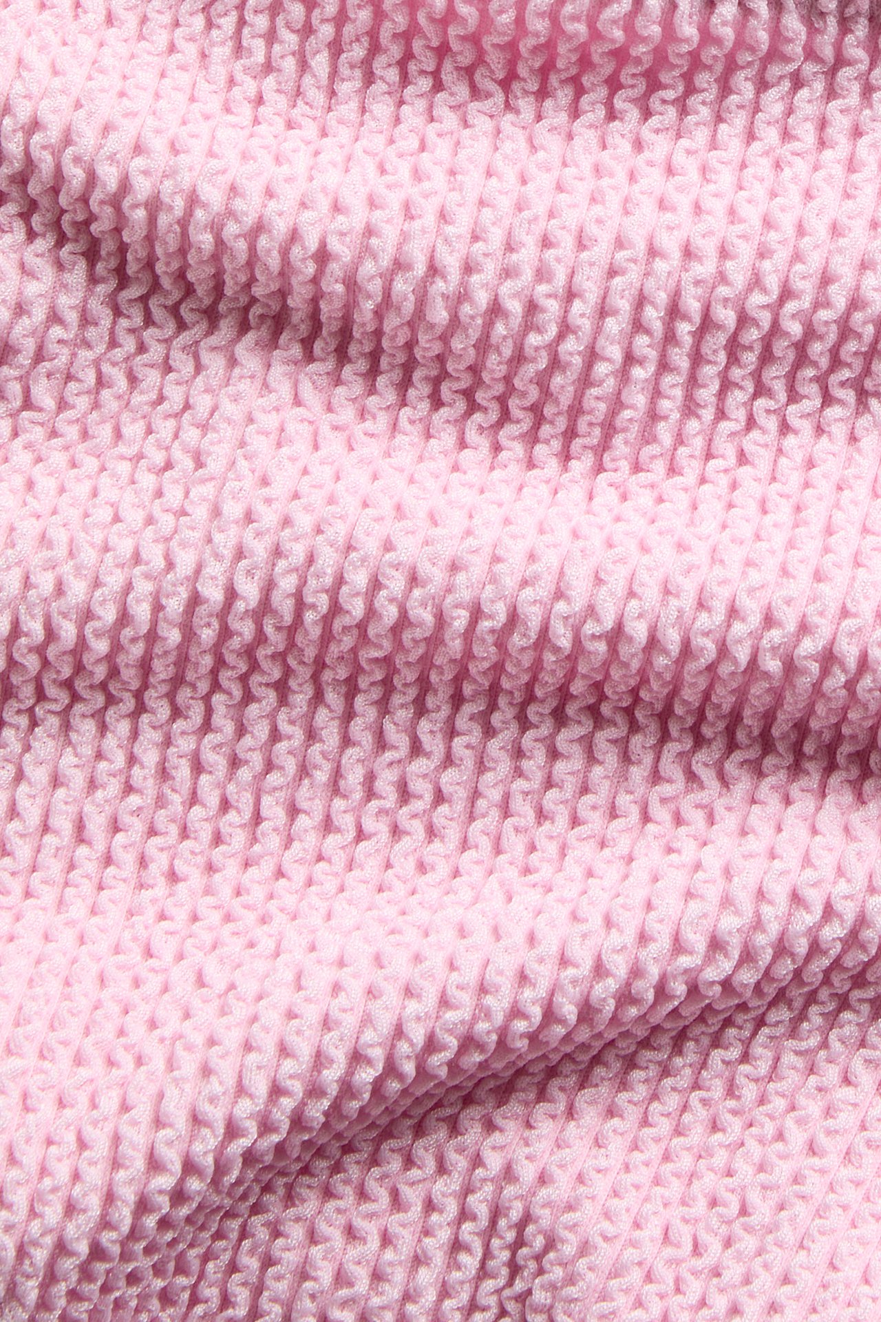 Nærbilde av rosa strukturert stoff til en høytlivs brazilian bikinitruse.