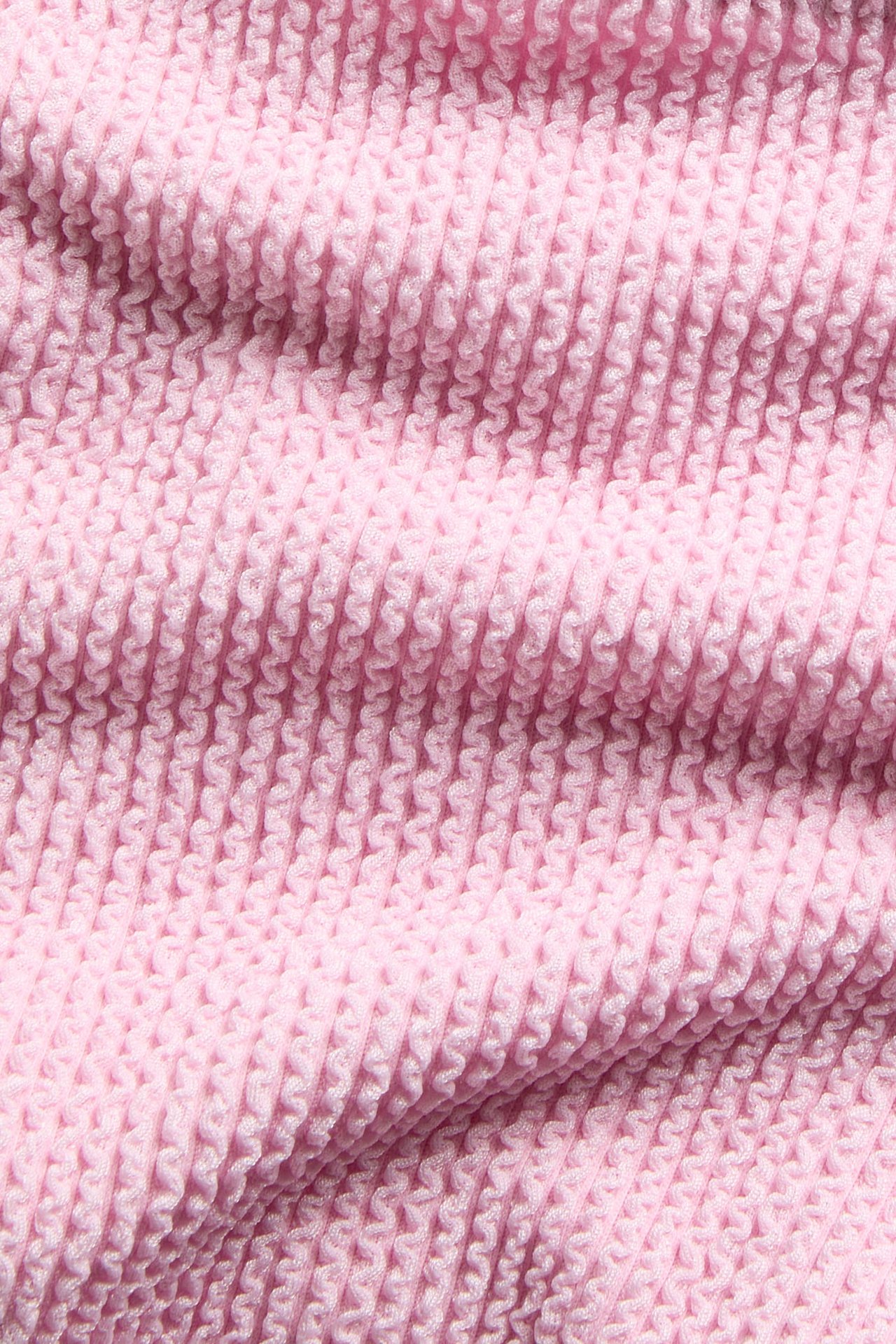 Zbliżenie na różowy strukturalny materiał, część wysokiego dołu od bikini brazilian.