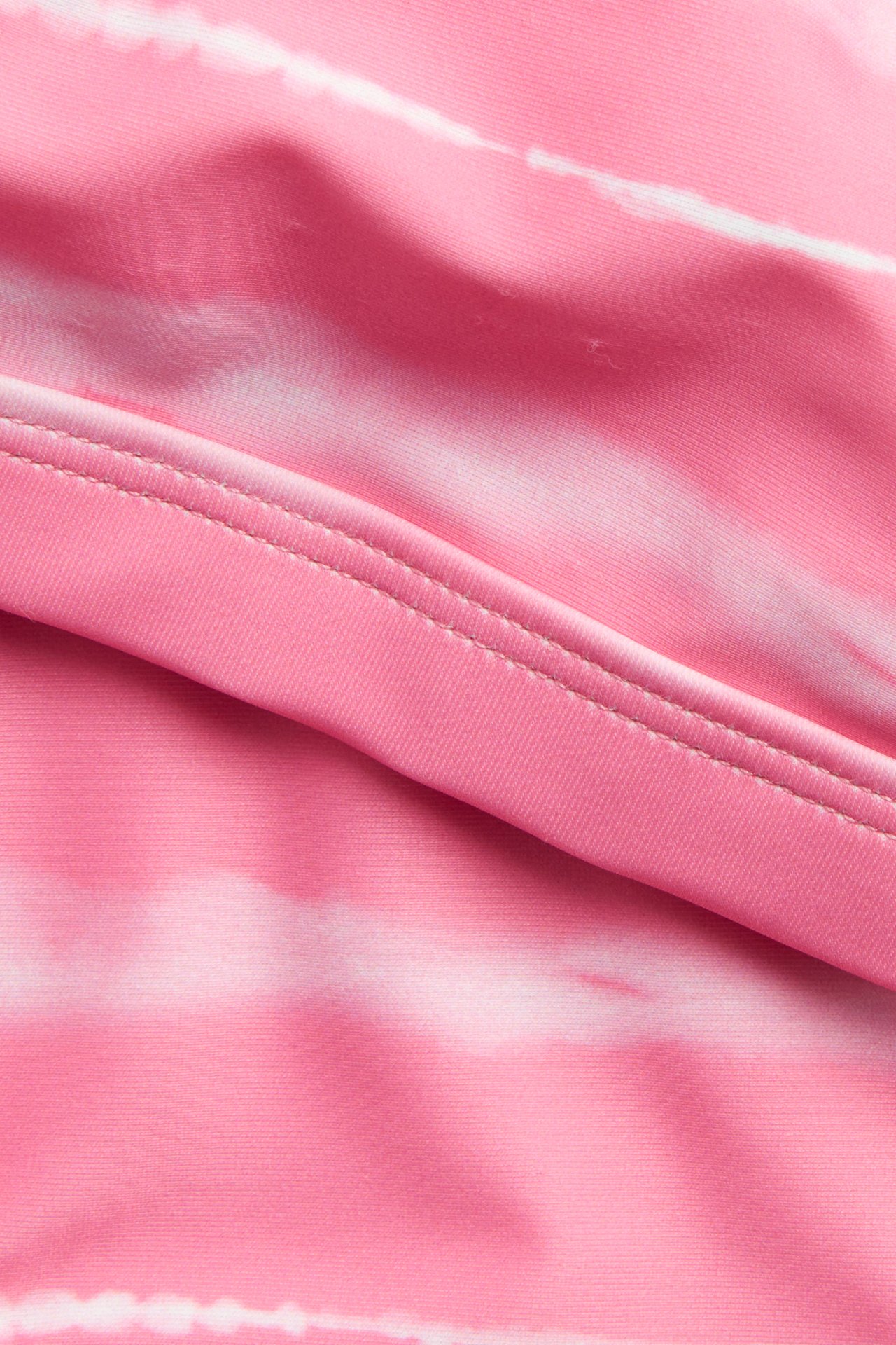 Närbild av ljusrosa batikmönstrat bikiniväv med en synlig söm.