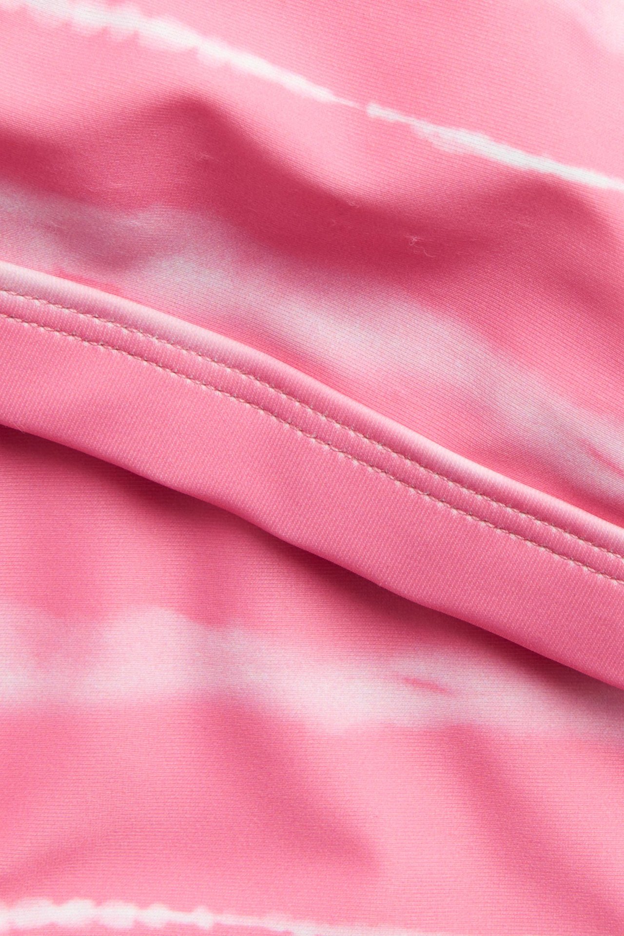 Zbliżenie na jasnoróżowy materiał bikini we wzór batik z widocznym szwem.