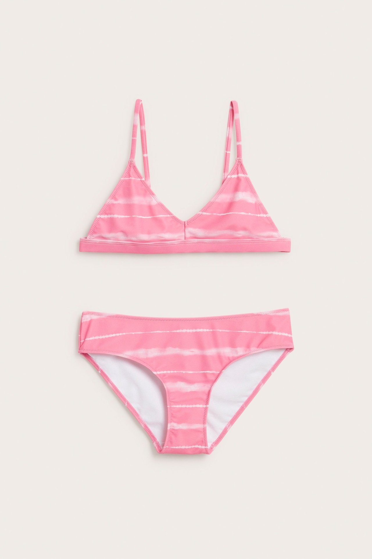 Widok z przodu jasnoróżowego bikini dziecięcego w batikowy wzór z wąskimi ramiączkami.