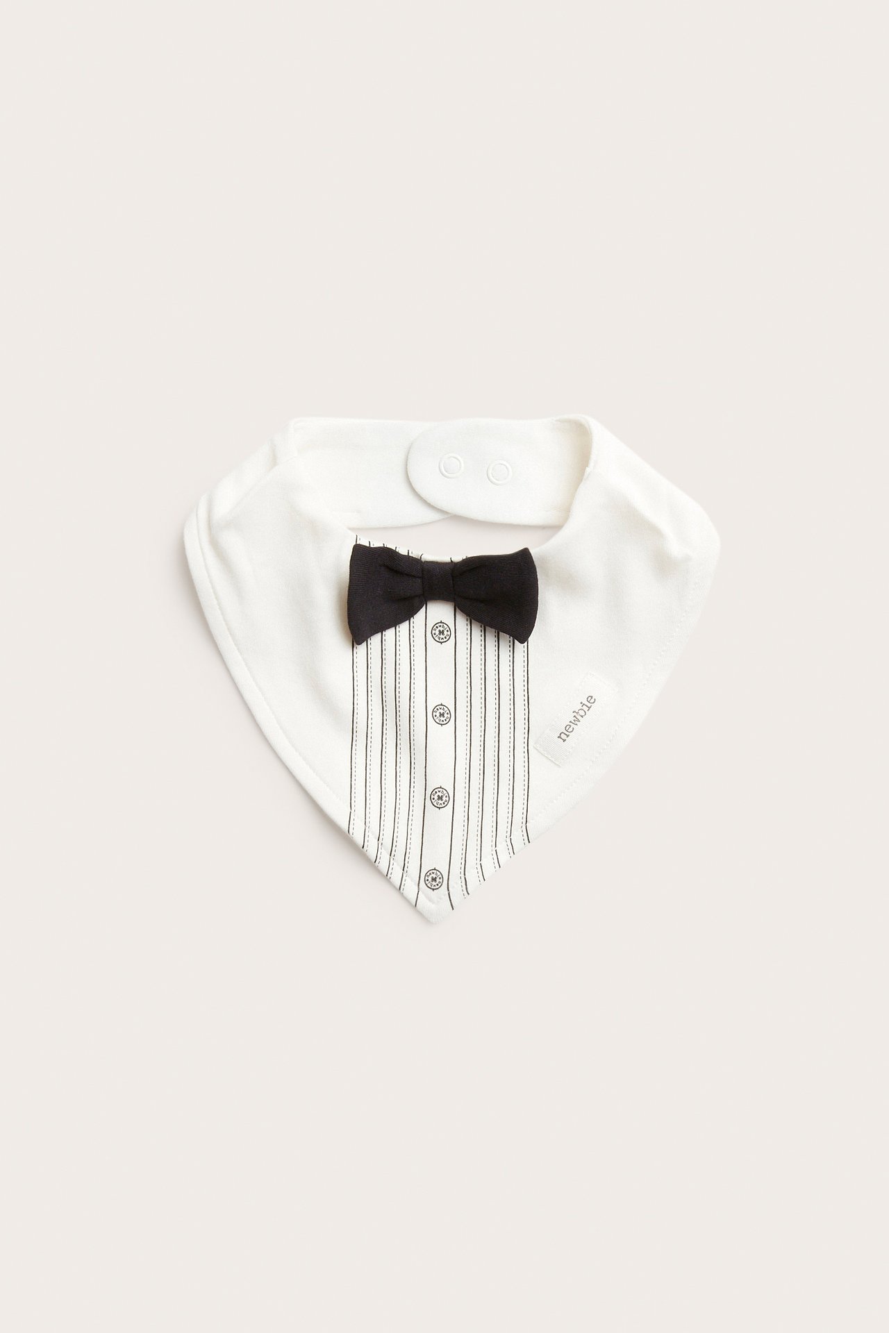 Frontbilde av en hvit baby smekke med smokingdesign, svart sløyfe og knapper.