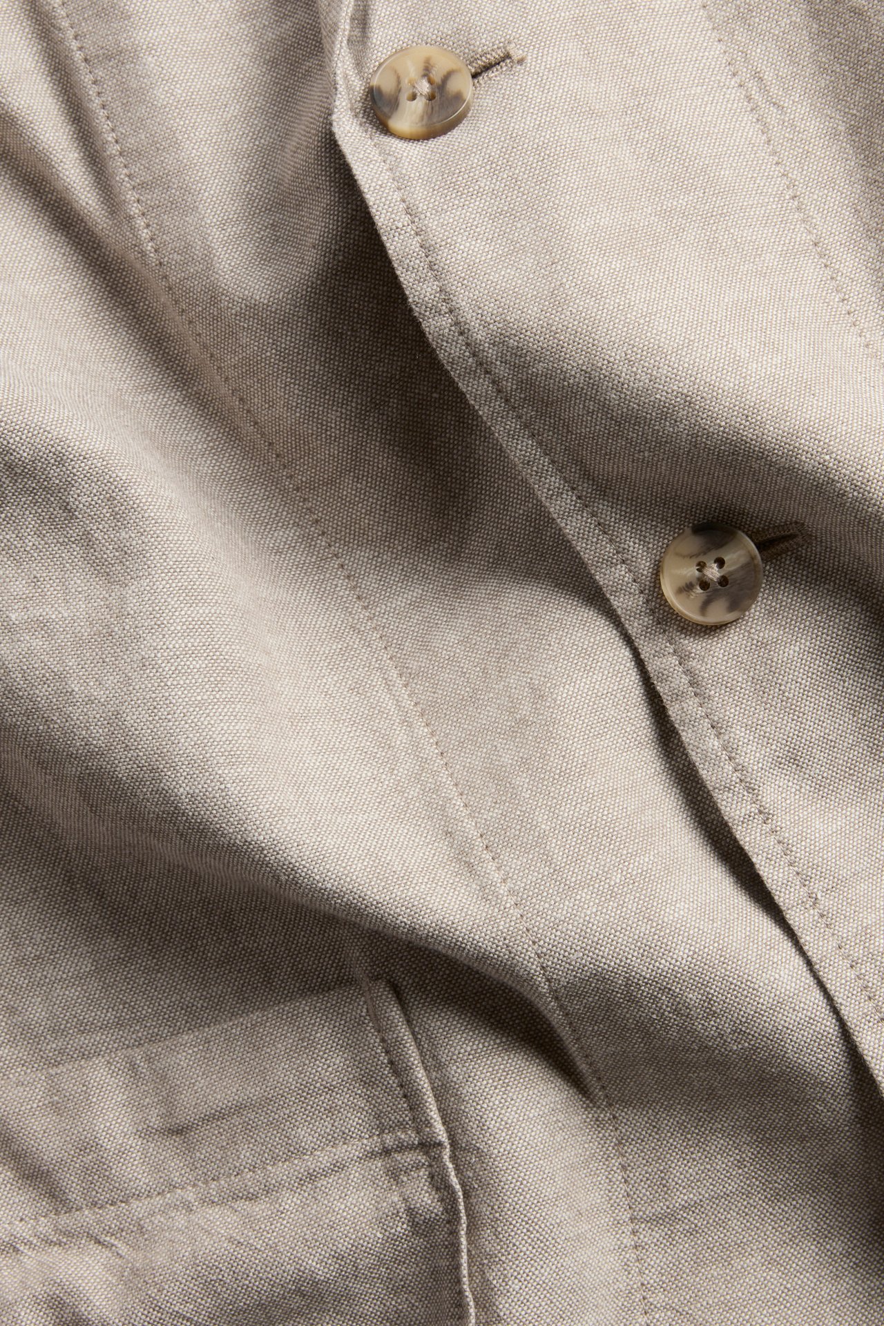 Lähikuva miesten beigestä regular fit pellavasekoitekavajista, jossa on marmoroidut napit.