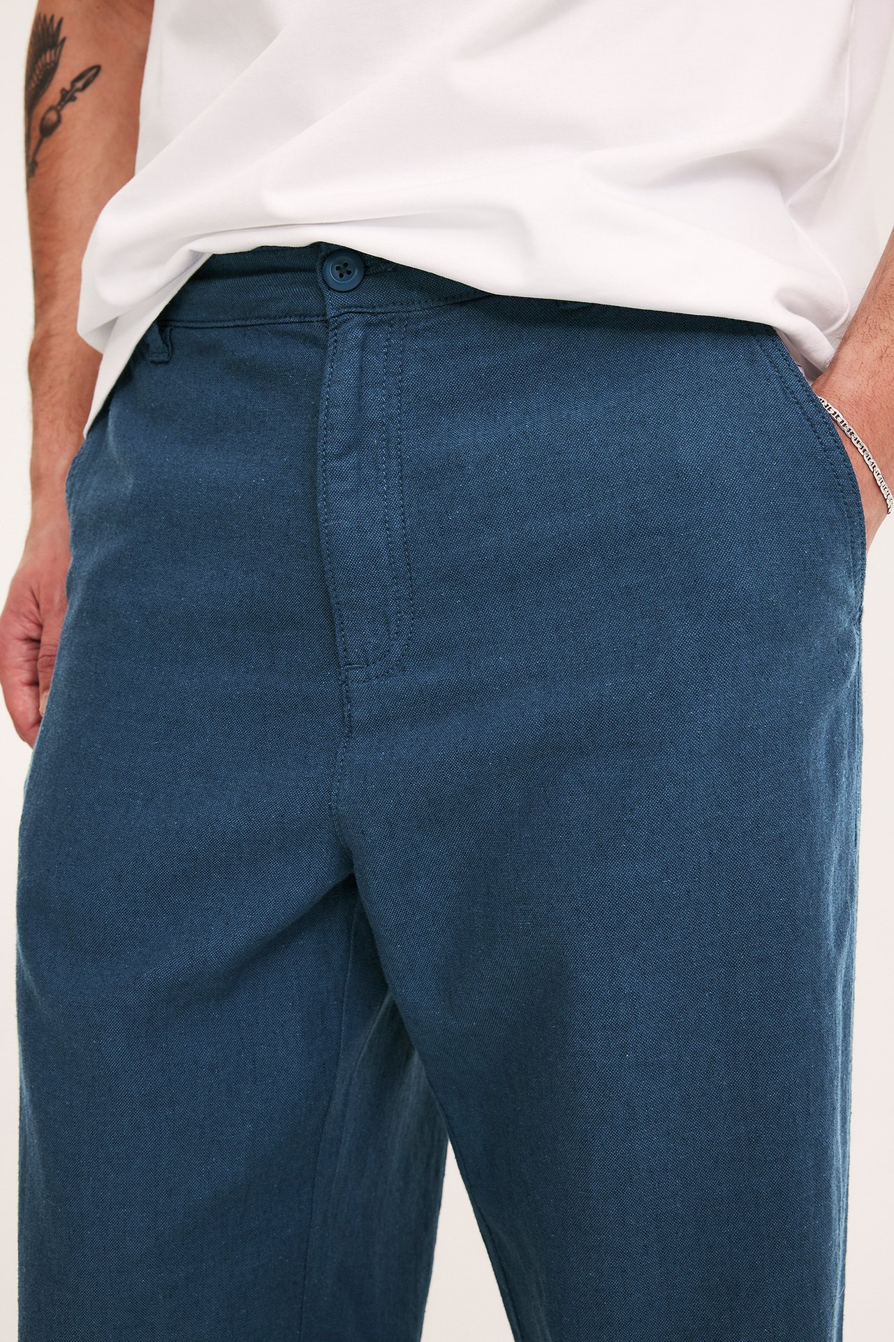 Zbliżenie na mężczyznę w niebieskich spodniach z mieszanki lnu o regularnym kroju i białym T-shircie.