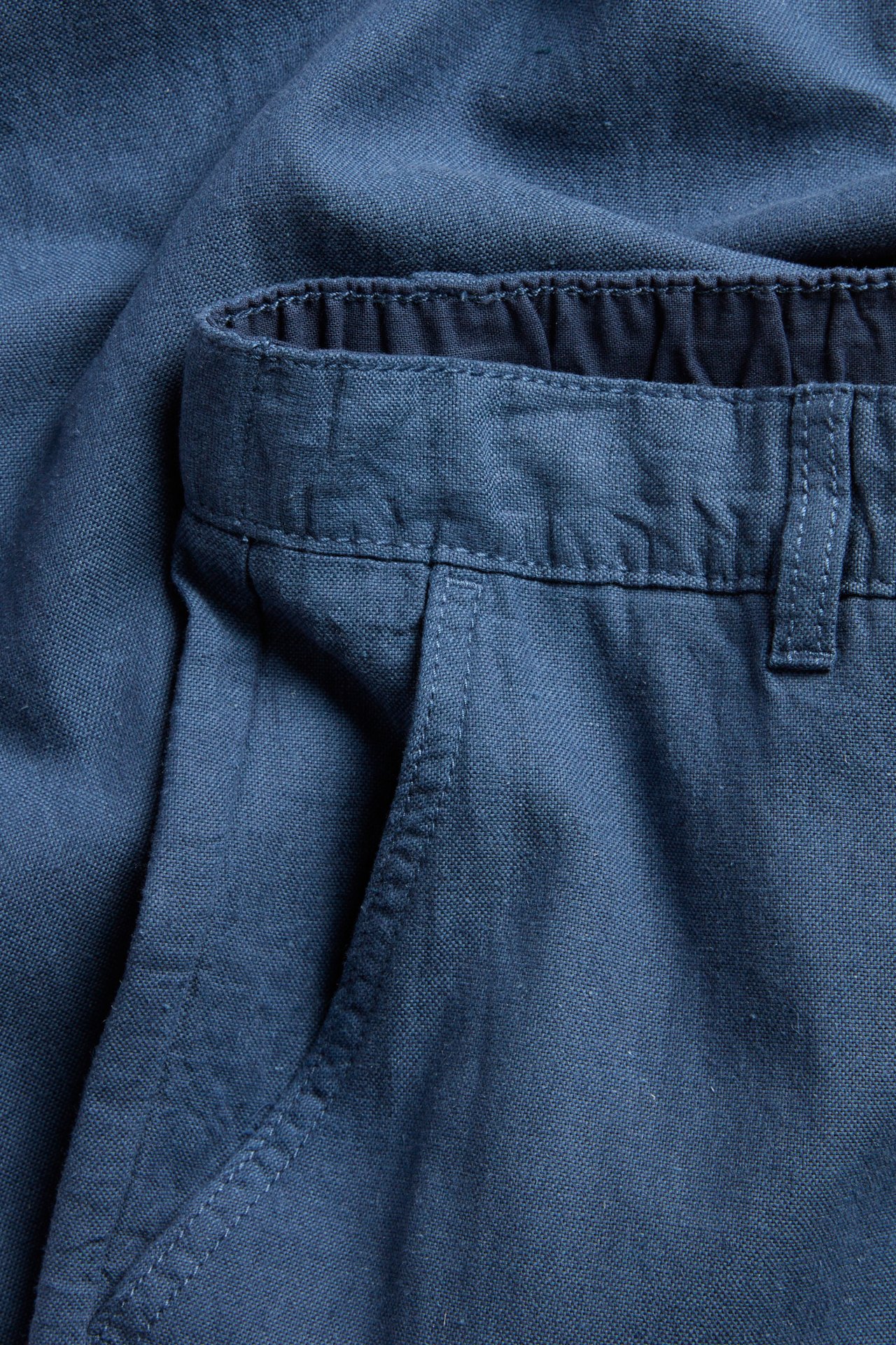 Lähikuva sinisistä pellavasekoitehousuista, joissa joustovyötärö takana ja kiristysnyöri.