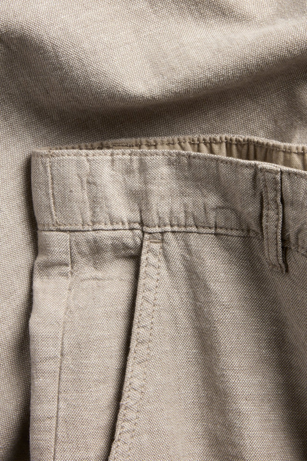 Zbliżenie na jasnobrązowe męskie spodnie z mieszanki lnu z elastycznym pasem i kieszenią.