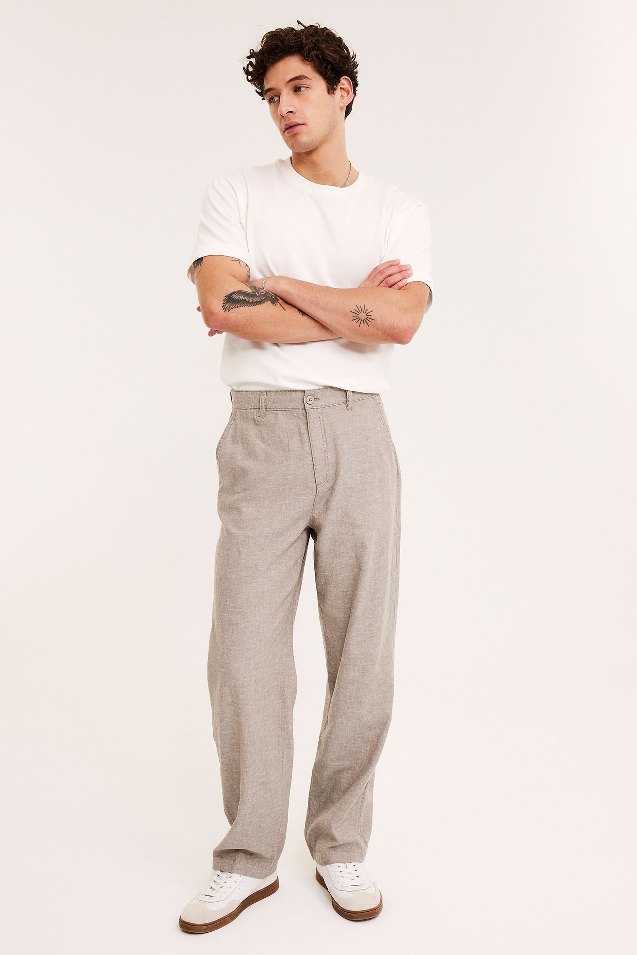 Mann forfra i lysebrune regular fit linblandingbukser, hvit t-skjorte og hvite sneakers.