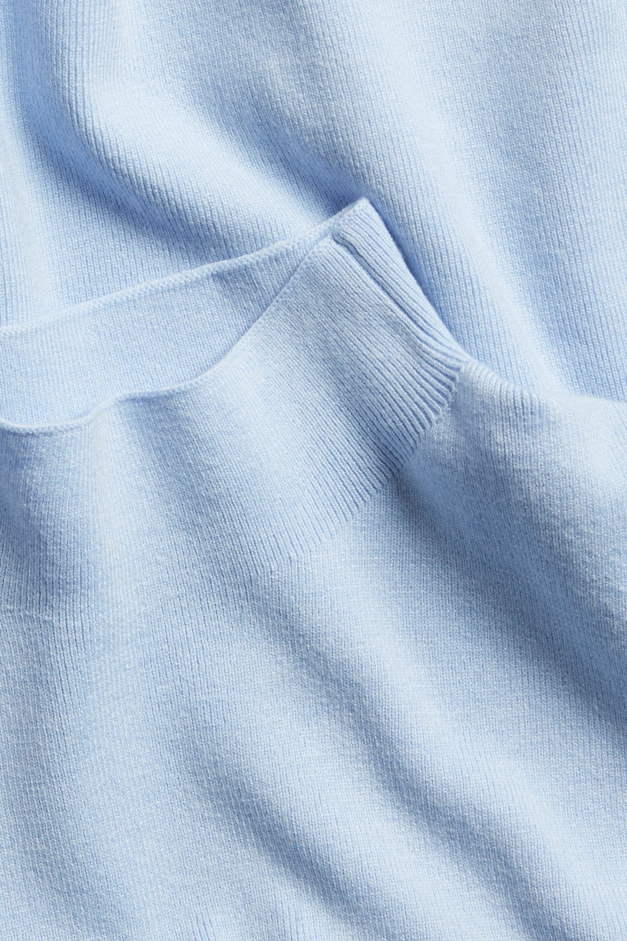 Zbliżenie jasnoniebieskiego swetra dzianinowego z prążkowanym kołnierzem i miękką fakturą.