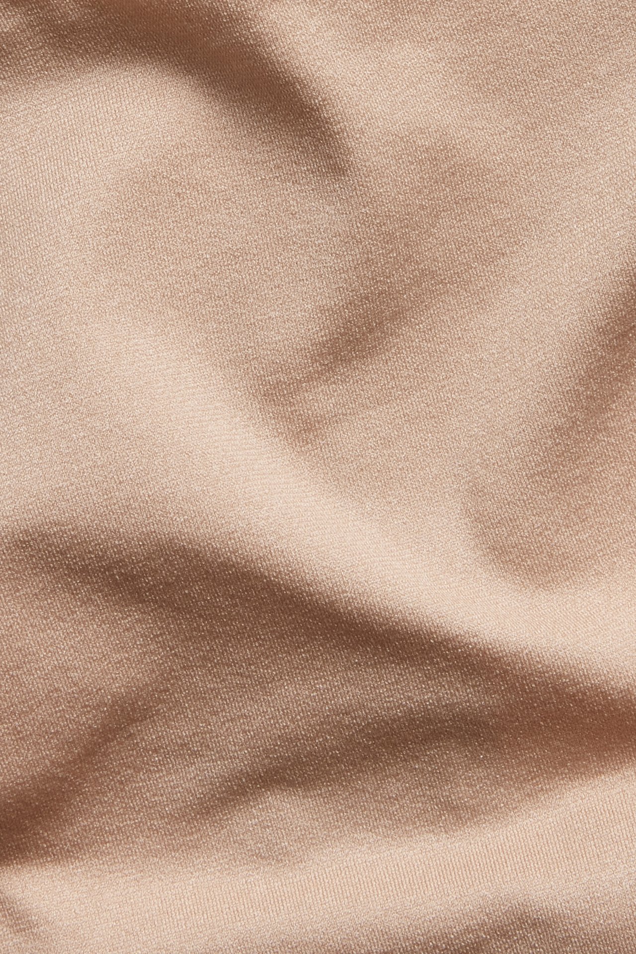 Lähikuva yksivärisestä beigestä, pehmeästä ja joustavasta stringhousujen kankaasta.