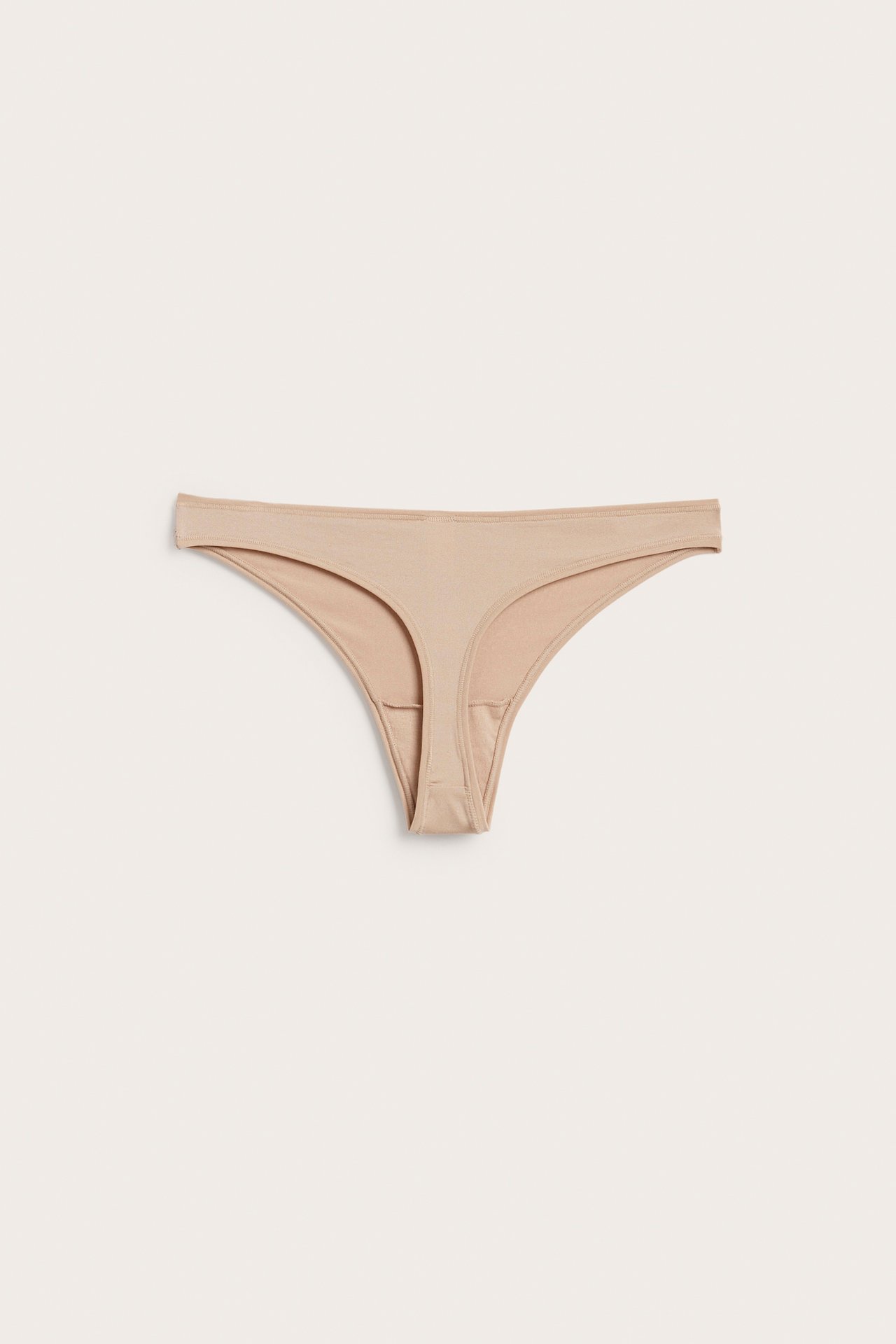 Framifrån, beige stringtrosa.
