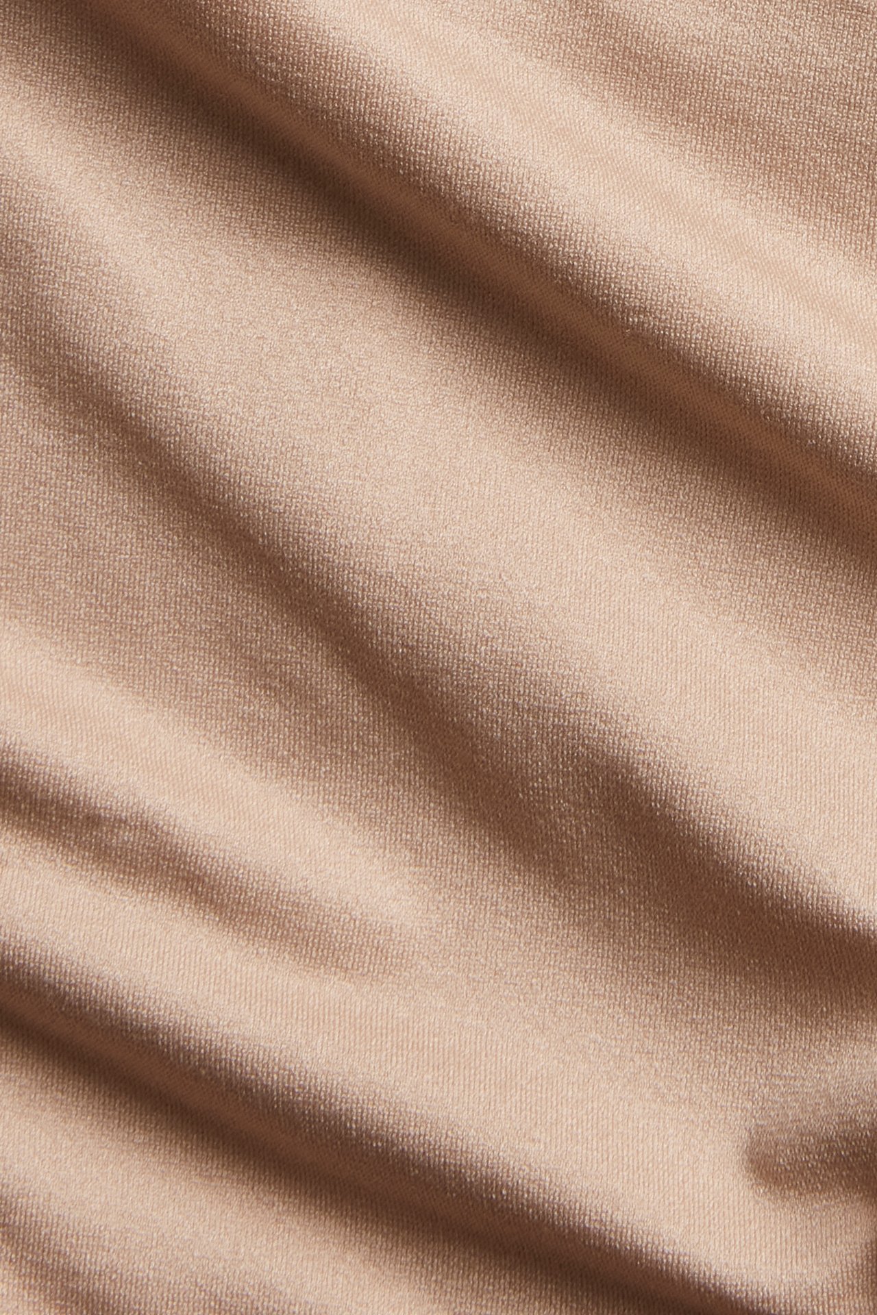 Lähikuva ruskeasta, pehmeästä, joustavasta, yksivärisestä kankaasta, todennäköisesti brazilian-alushousuihin.