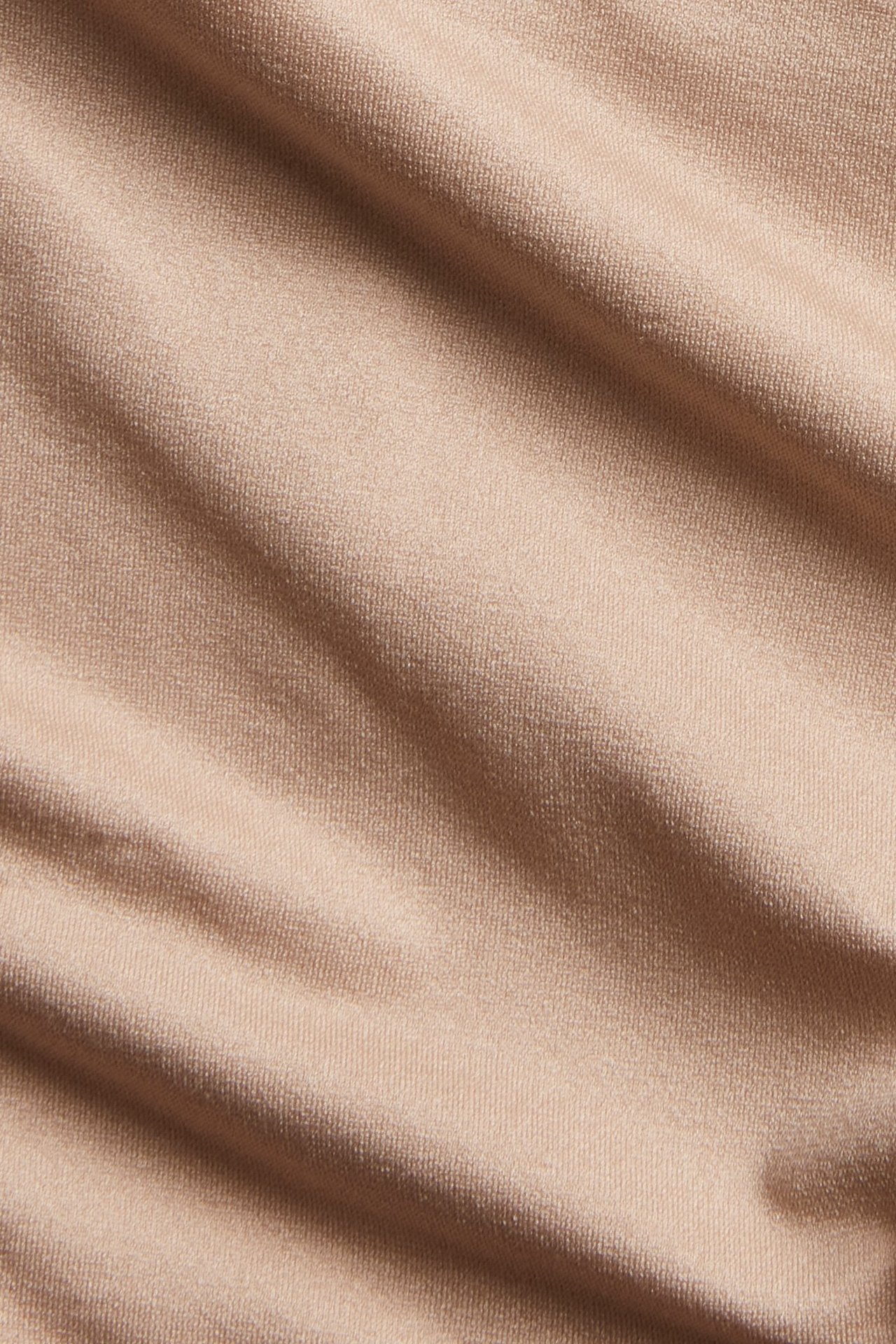 Lähikuva ruskeasta, pehmeästä, joustavasta, yksivärisestä kankaasta, todennäköisesti brazilian-alushousuihin.